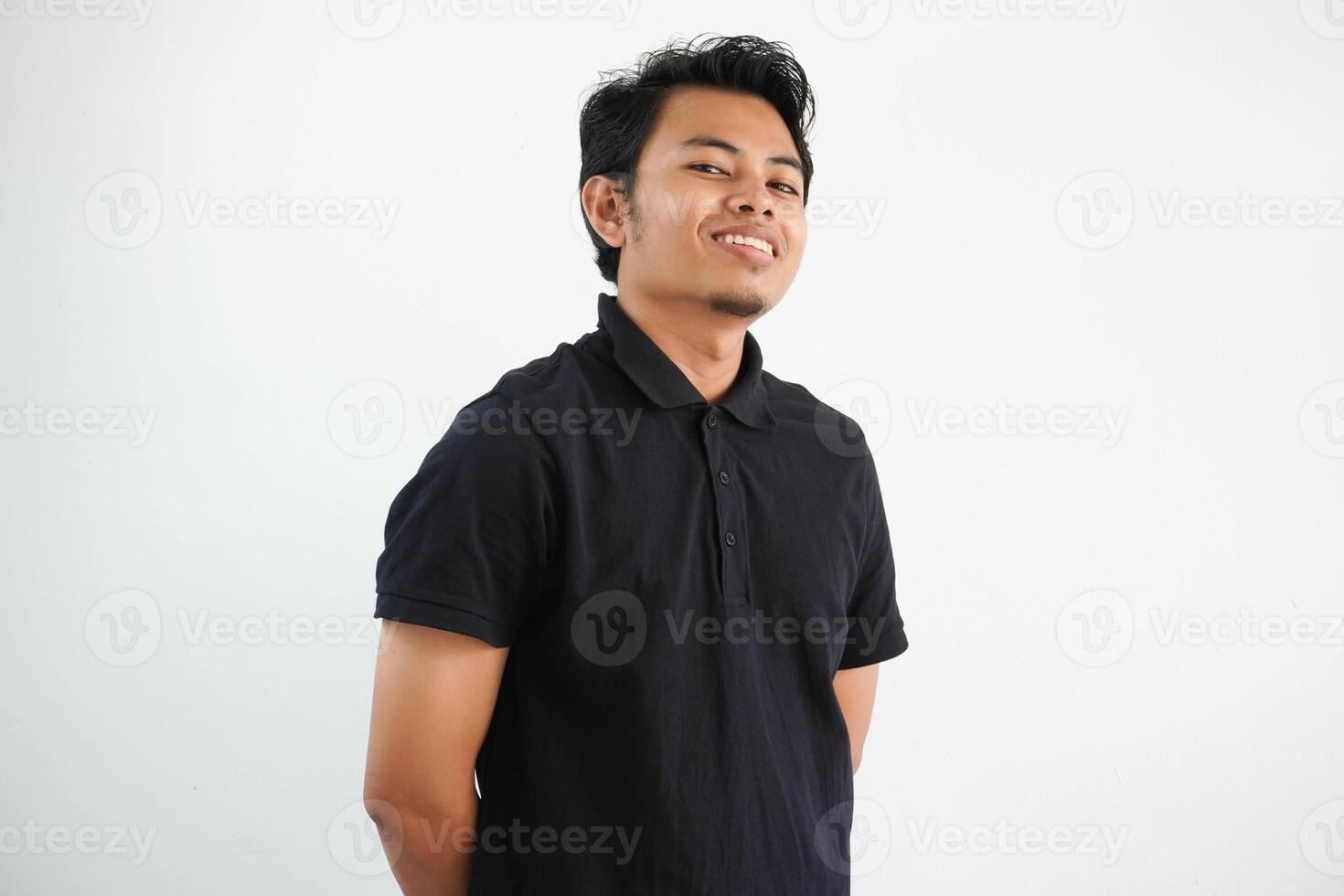 giovane asiatico uomo indossare nero polo t camicia felice, sorridente e allegro guardare a telecamera isolato su bianca sfondo foto