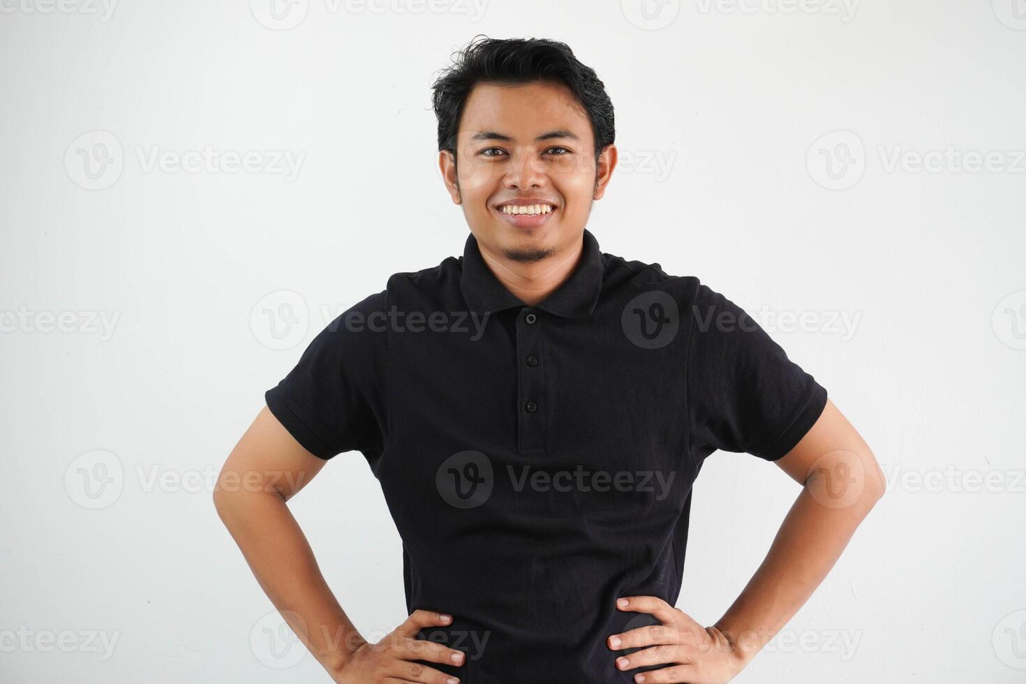 sorridente giovane asiatico uomo mostrando eccitato espressione con tutti e due mano su il suo vita indossare nero polo t camicia isolato su bianca sfondo foto