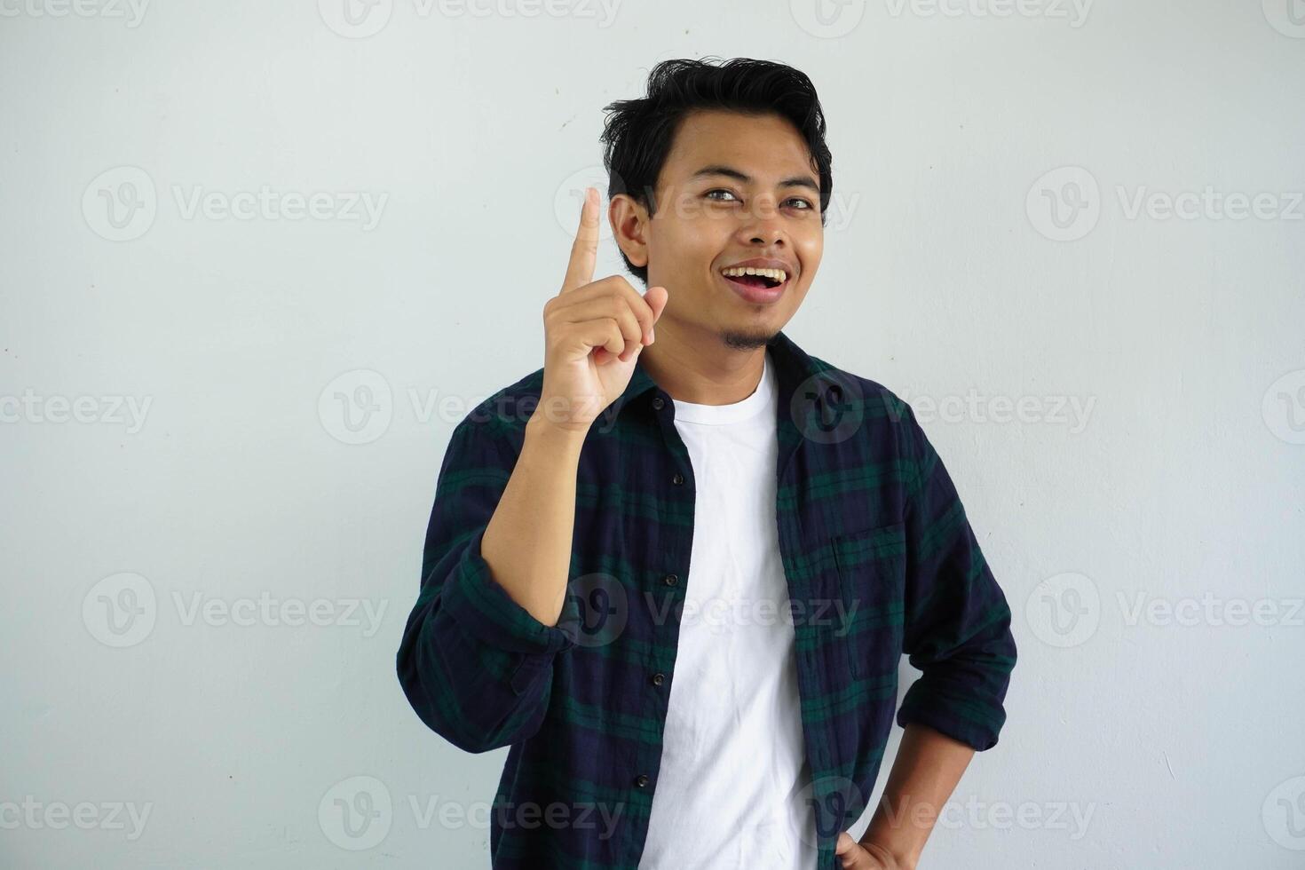 giovane asiatico uomo mostrando eccitato viso espressione con dito puntamento su isolato su bianca sfondo foto