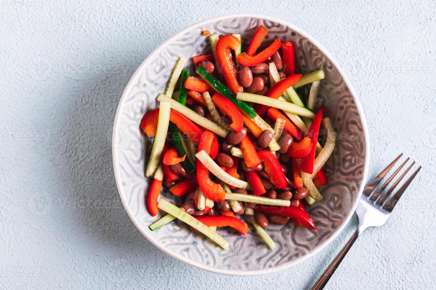 vicino su di vegetariano insalata di rosso fagioli, cetriolo e campana Pepe nel un' ciotola su il tavolo superiore Visualizza foto