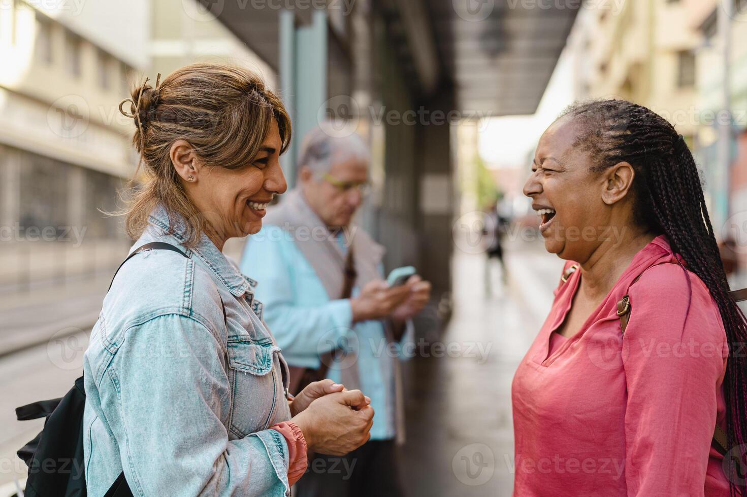 contento multirazziale donne amici parlando mentre in attesa a il autobus stazione foto