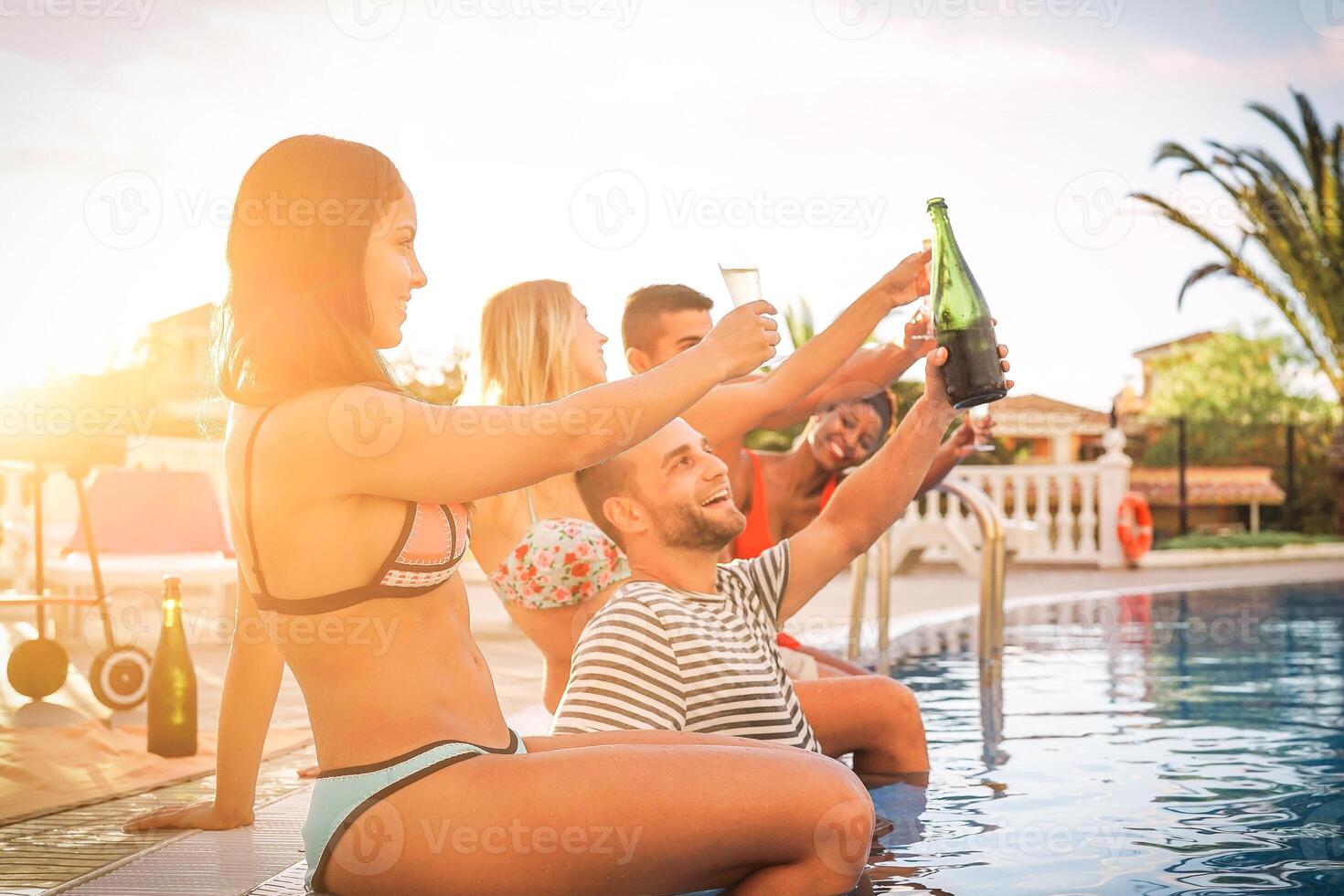 gruppo di contento amici fabbricazione un' piscina festa a tramonto - giovane persone ridendo e avendo divertimento potabile Champagne a barbecue festa in piscina nel vacanza - amicizia, vacanze, gioventù stile di vita concetto foto