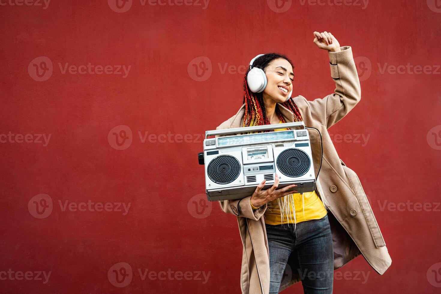 contento giovane ragazza avendo divertimento danza mentre ascoltando musica con cuffie e Vintage ▾ Boombox stereo foto