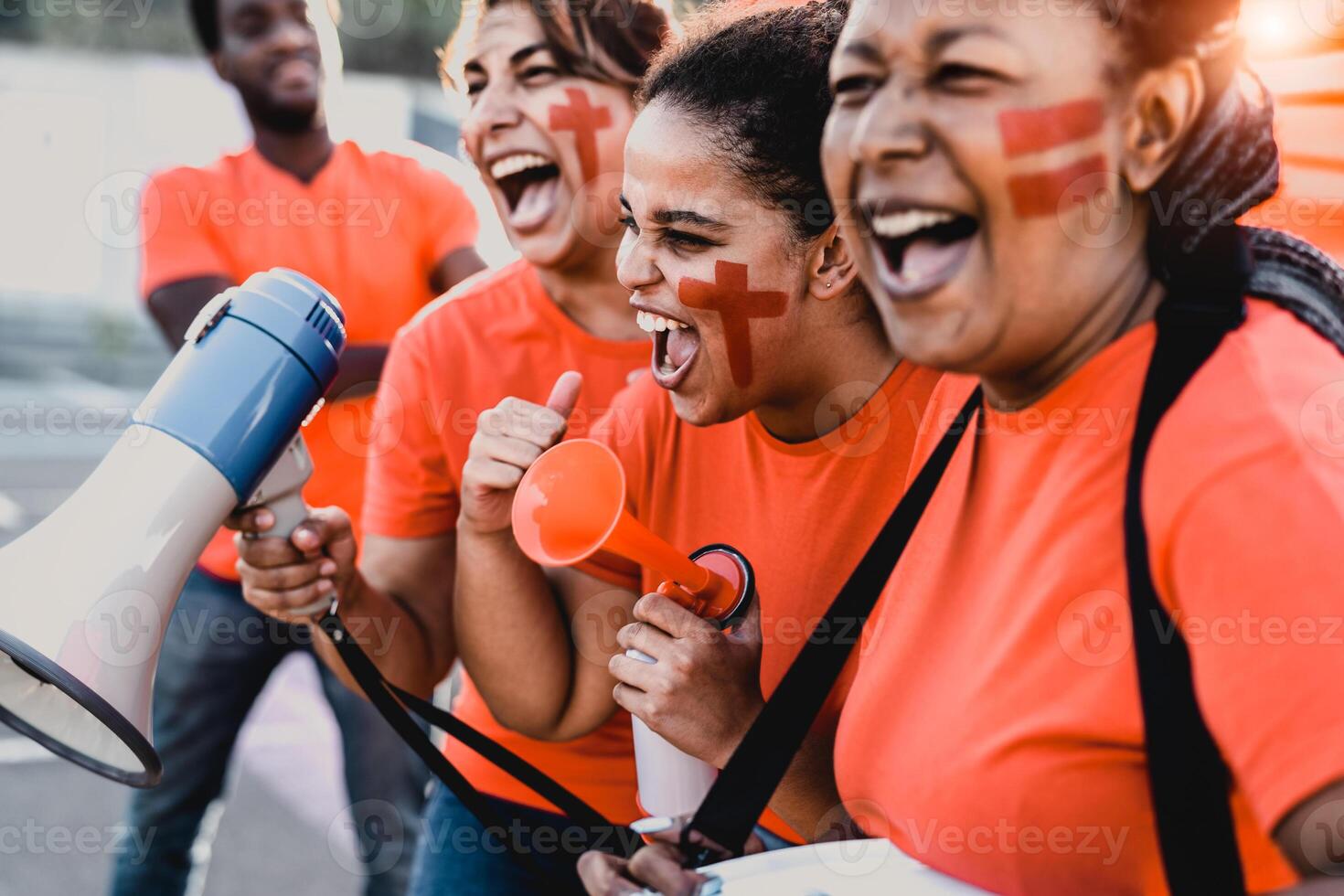 femmine calcio fan esultante mentre Guardando calcio gioco a stadio - donne con dipinto viso e megafono incoraggiando loro squadra - sport divertimento concetto foto