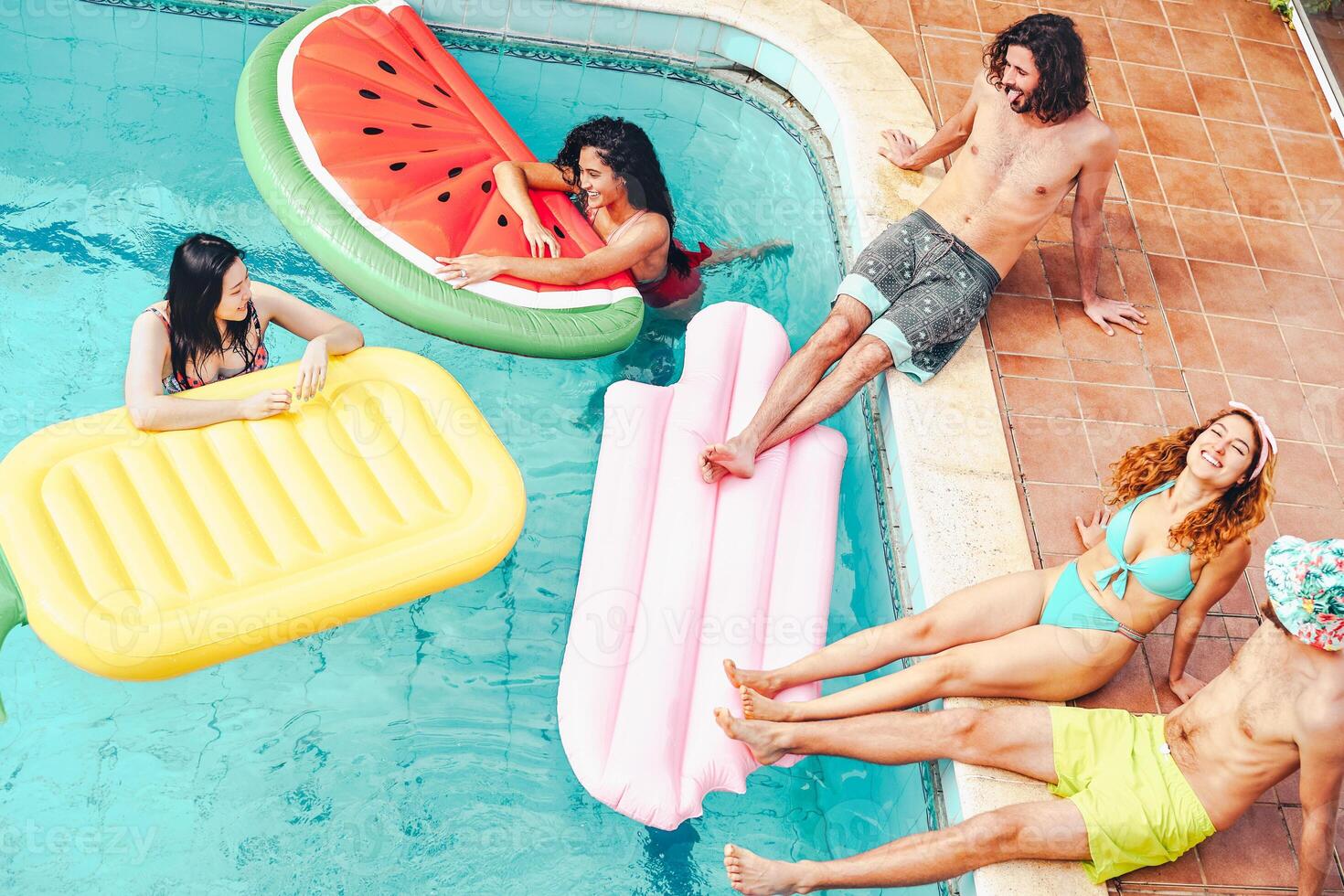 contento amici avendo divertimento nel nuoto piscina durante estate tropicale vacanza - giovane persone rilassante e galleggiante su aria lilos nel il piscina ricorrere - amicizia, relax, vacanze e gioventù stile di vita concetto foto