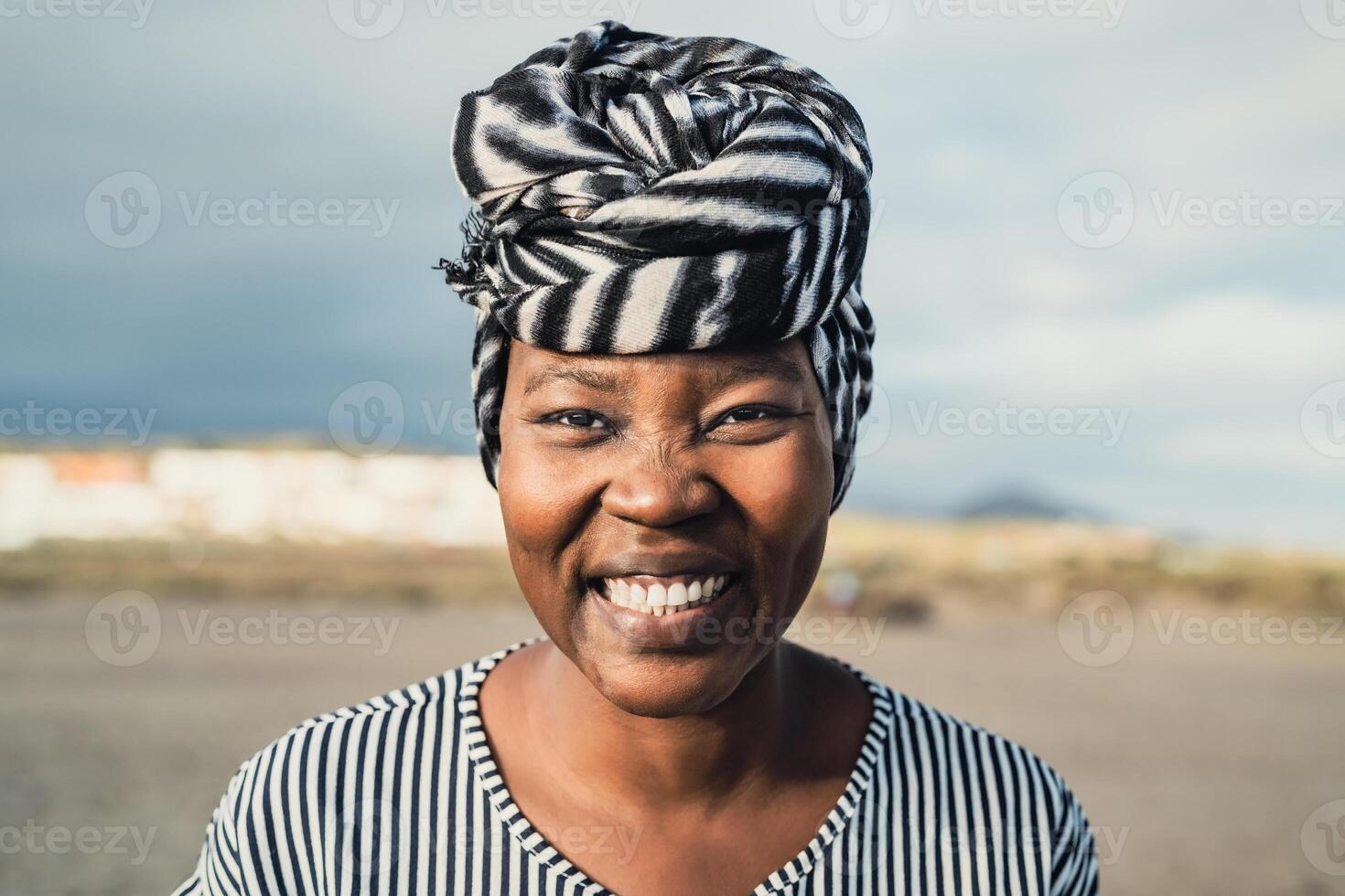 contento musulmano africano donna indossare turbante sorridente nel telecamera su il spiaggia durante estate vacanza foto