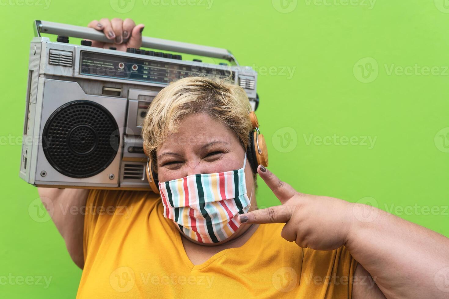 più dimensione donna ascoltando per musica con senza fili cuffie mentre indossare viso protettivo maschera per evitare corona virus infezione - sovrappeso persone e Salute cura concetto foto