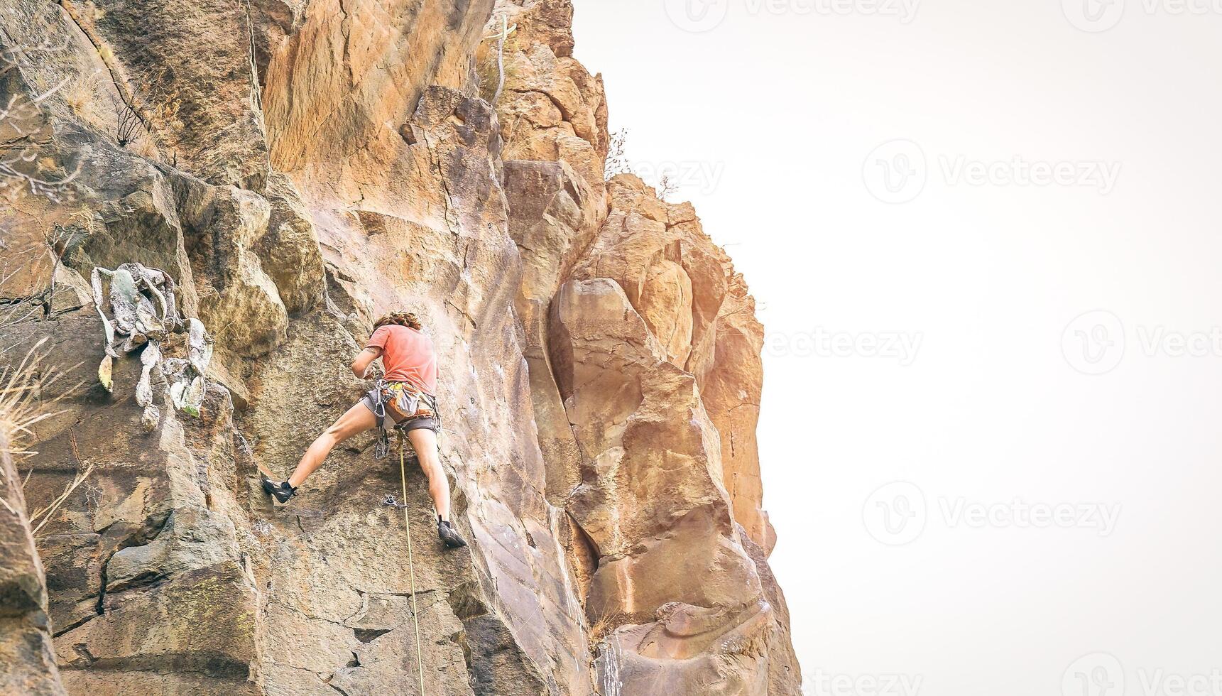 atletico uomo arrampicarsi un' roccia parete a tramonto - scalatore l'esecuzione su un' canyon montagna - concetto di sport e estremo stile di vita foto