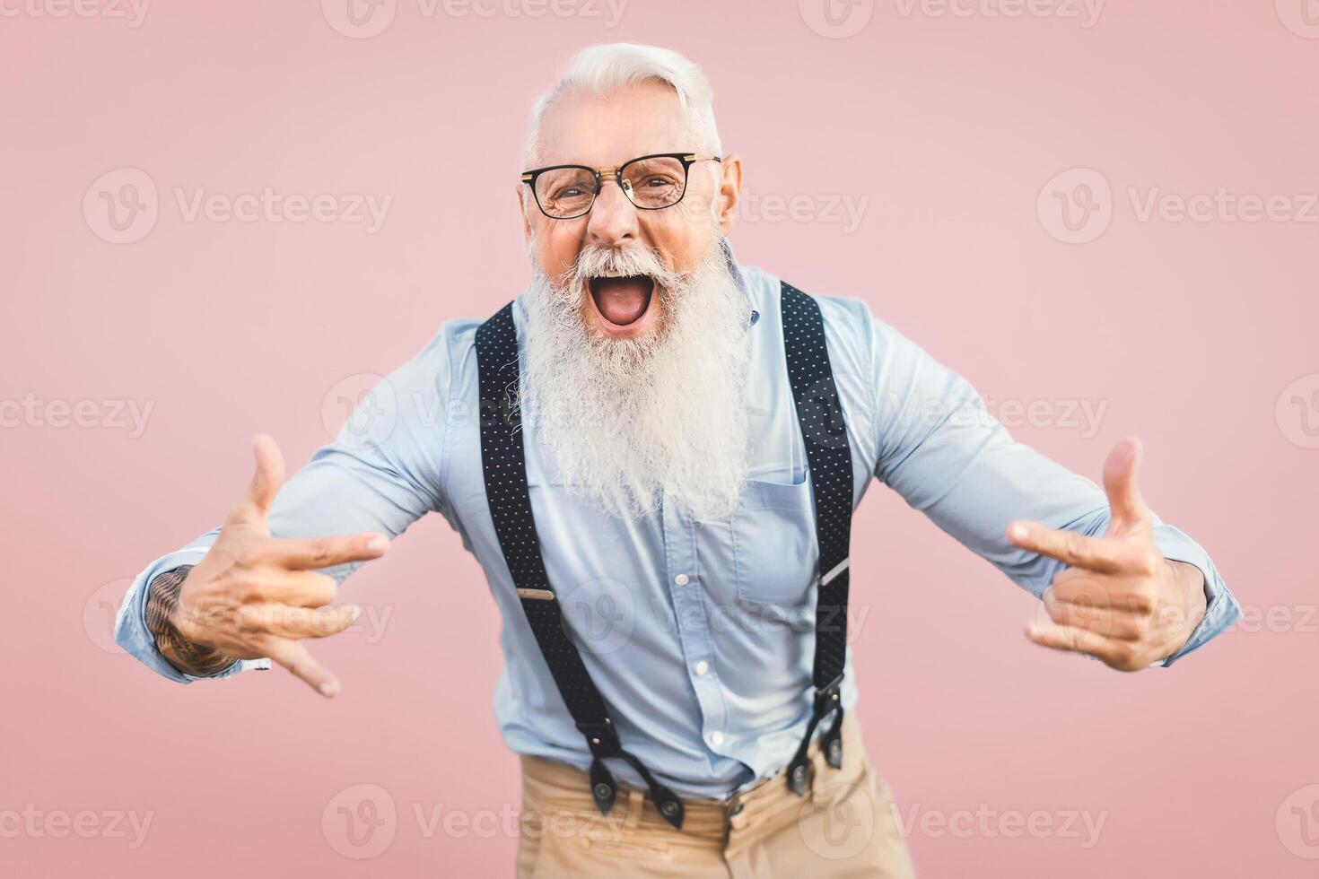 anziano uomo avendo divertimento in posa nel davanti telecamera - contento maturo maschio godendo pensionato tempo - anziano persone stile di vita e fricchettone cultura concetto - rosa sfondo foto