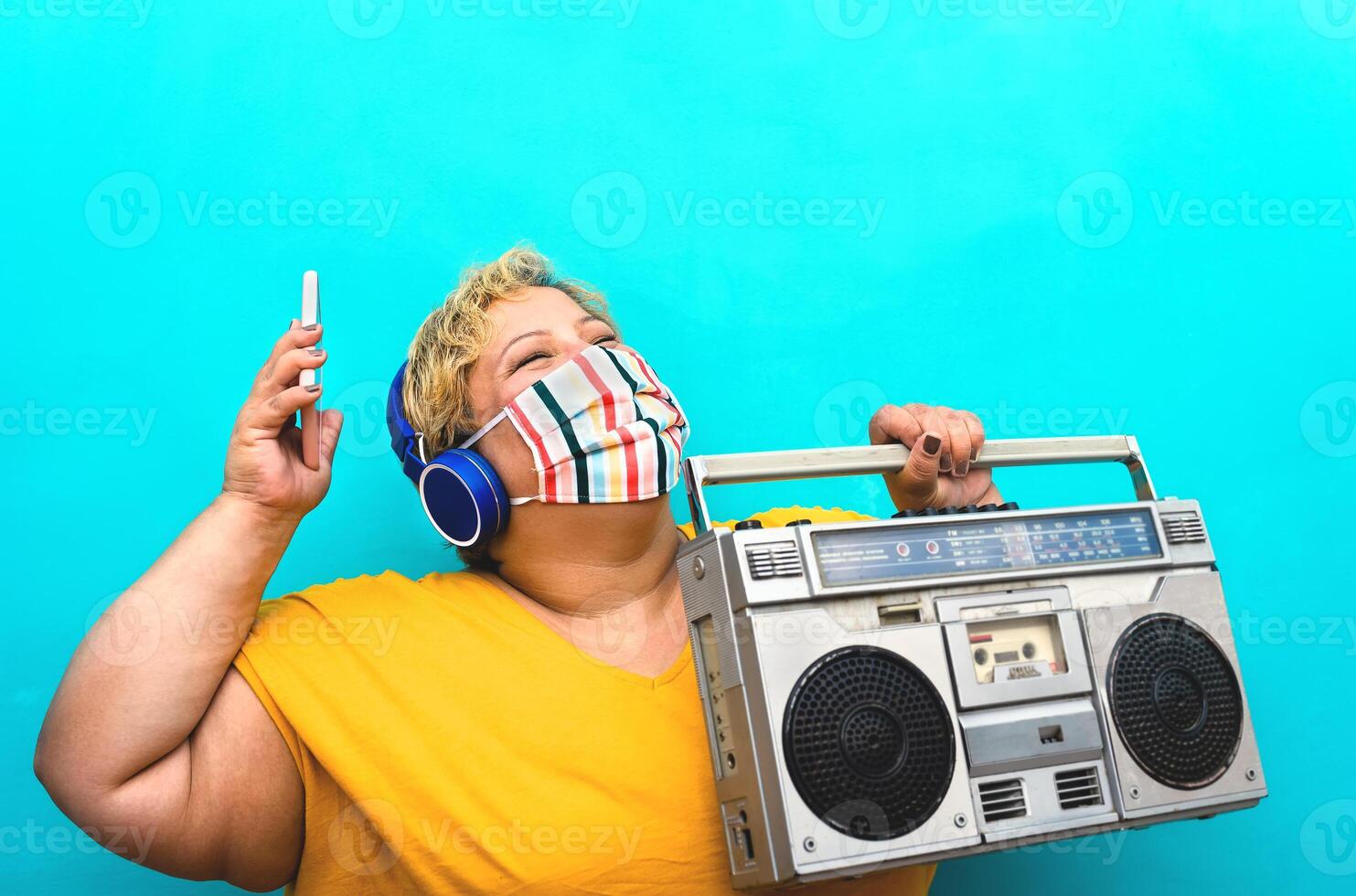 contento più dimensione donna ascoltando musica con mobile smartphone e cuffie mentre Tenere Vintage ▾ Boombox e indossare viso protettivo maschera per evitare corona virus infezione - sicurezza divertimento concetto foto