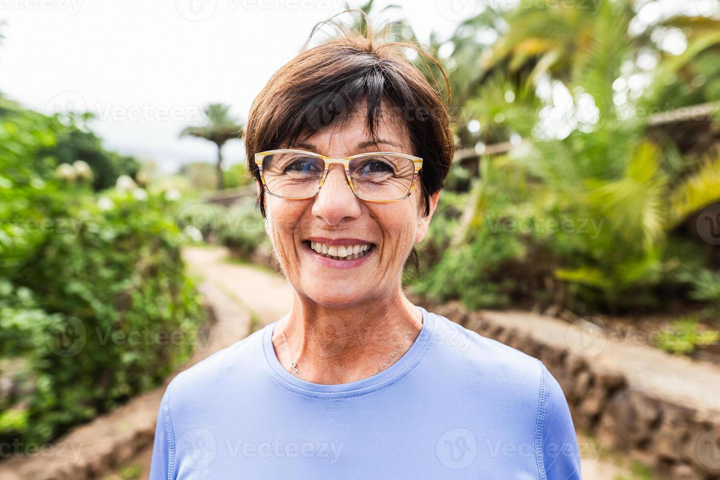 contento anziano donna avendo divertimento sorridente nel davanti di telecamera dopo formazione attività nel un' pubblico parco foto
