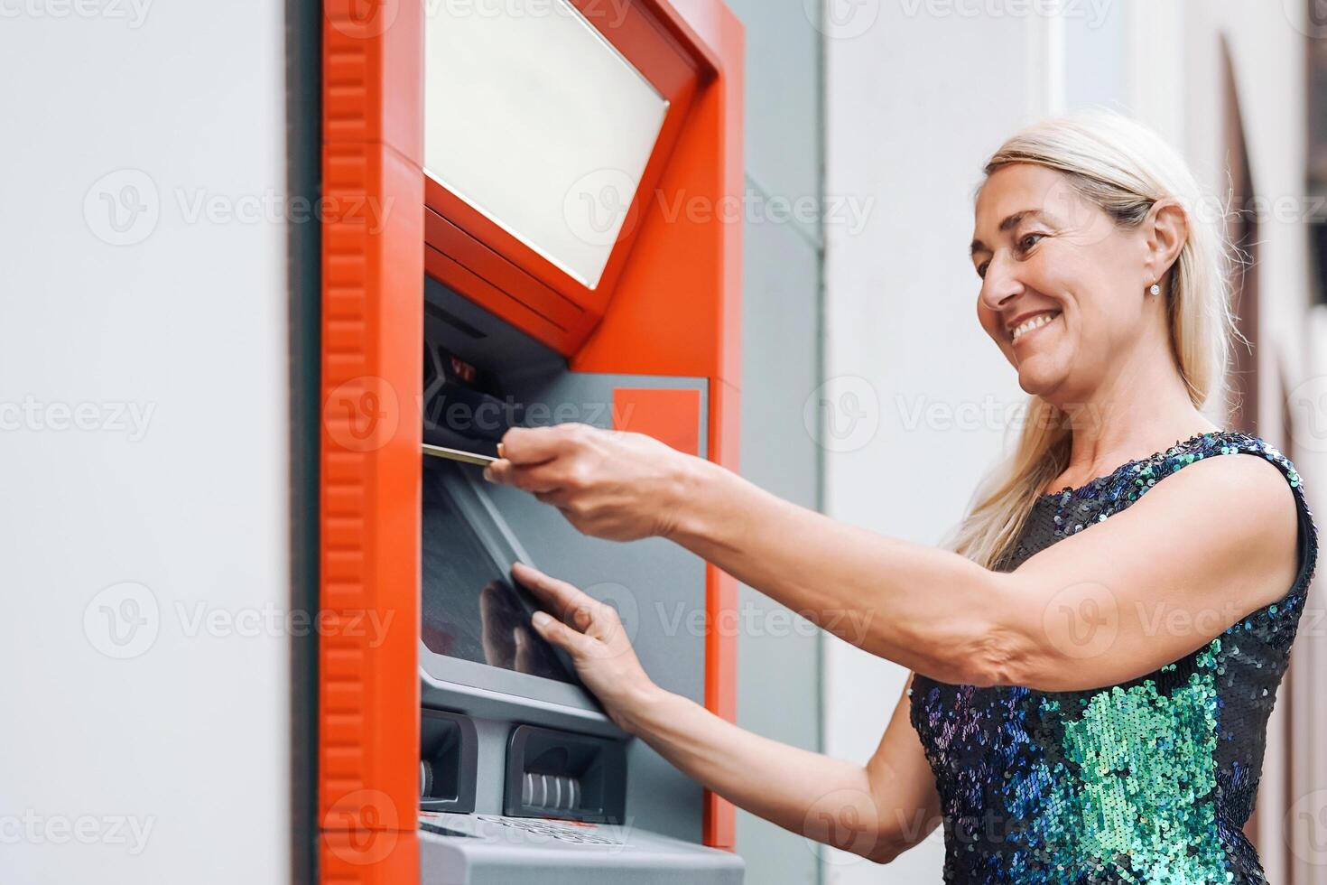 contento maturo donna ritirarsi i soldi a partire dal banca denaro contante macchina con addebito carta - anziano femmina fare pagamento con credito carta nel ATM - concetto di attività commerciale, bancario account e stile di vita persone foto