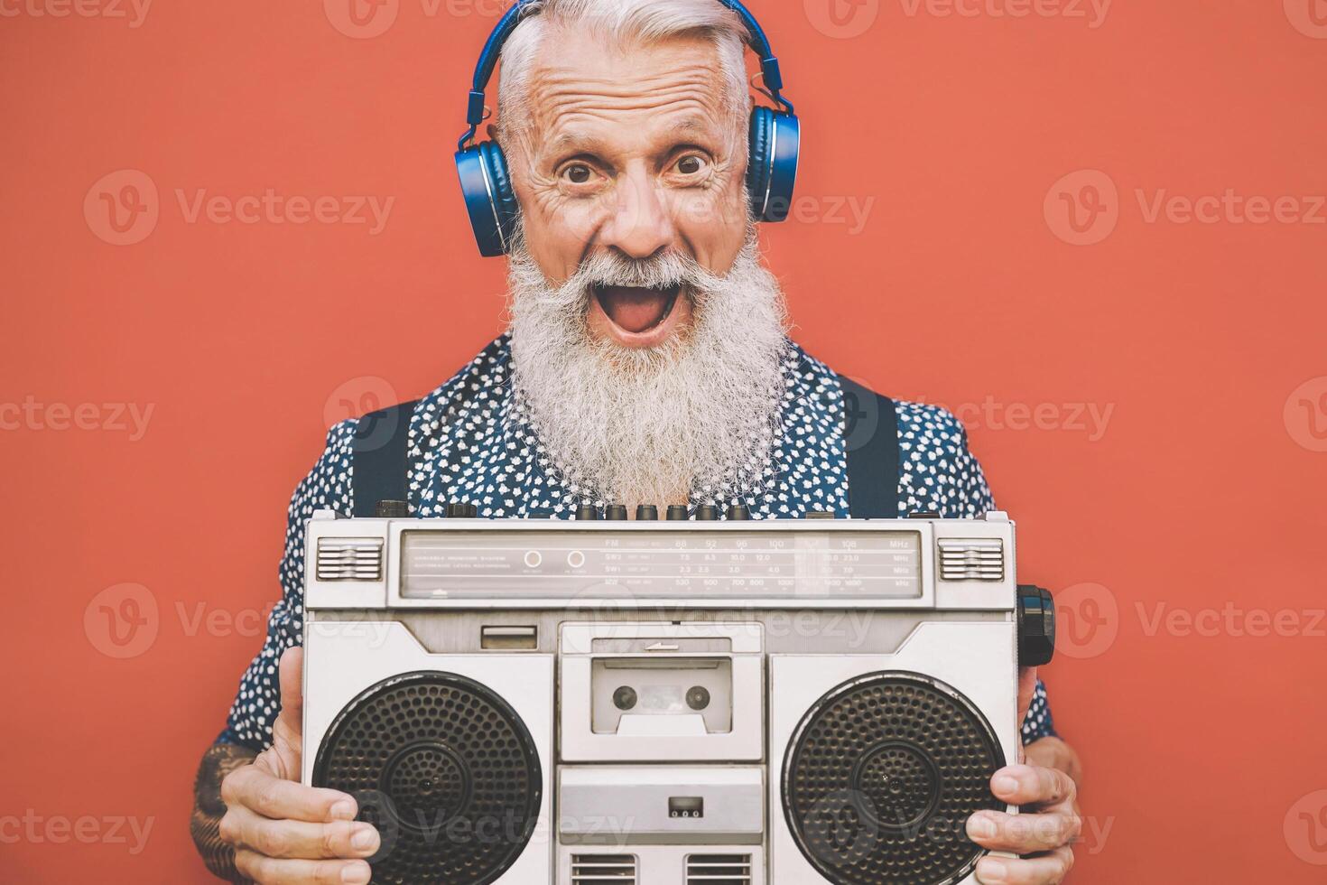 contento anziano uomo ascoltando per musica con Boombox e cuffie all'aperto - pazzo fricchettone maschio avendo divertimento con Vintage ▾ stereo - concetto di anziano persone stile di vita foto