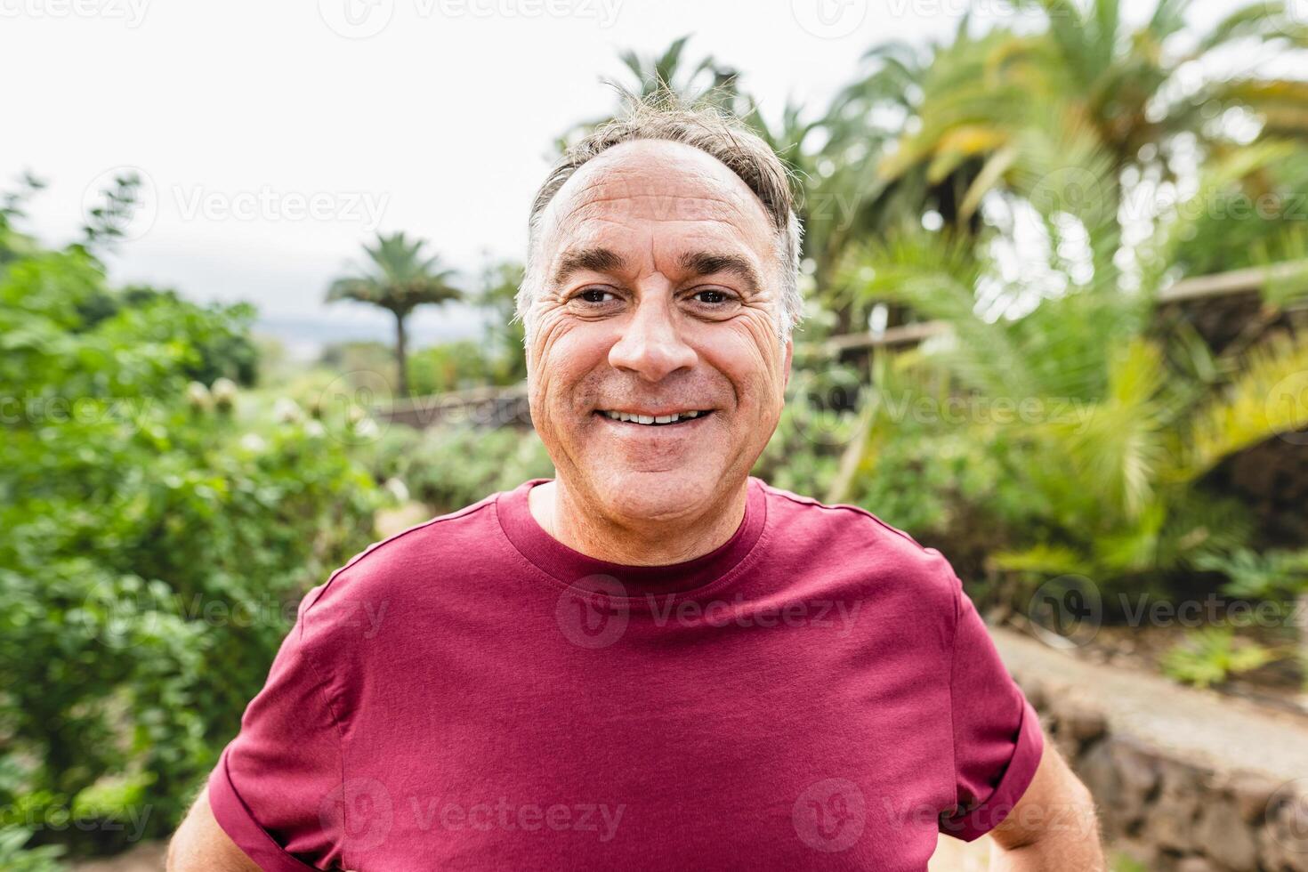 contento anziano uomo sorridente in il telecamera mentre fare gli sport attività nel un' pubblico parco foto