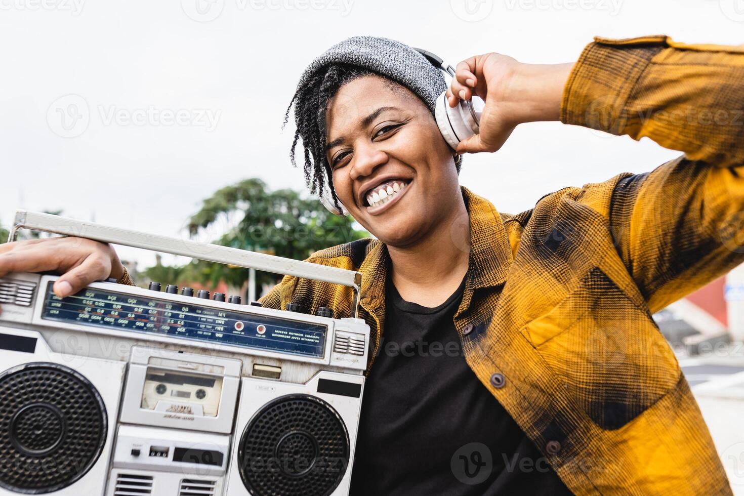 contento africano ragazza avendo divertimento ascoltando per musica con cuffie e Vintage ▾ Boombox stereo foto