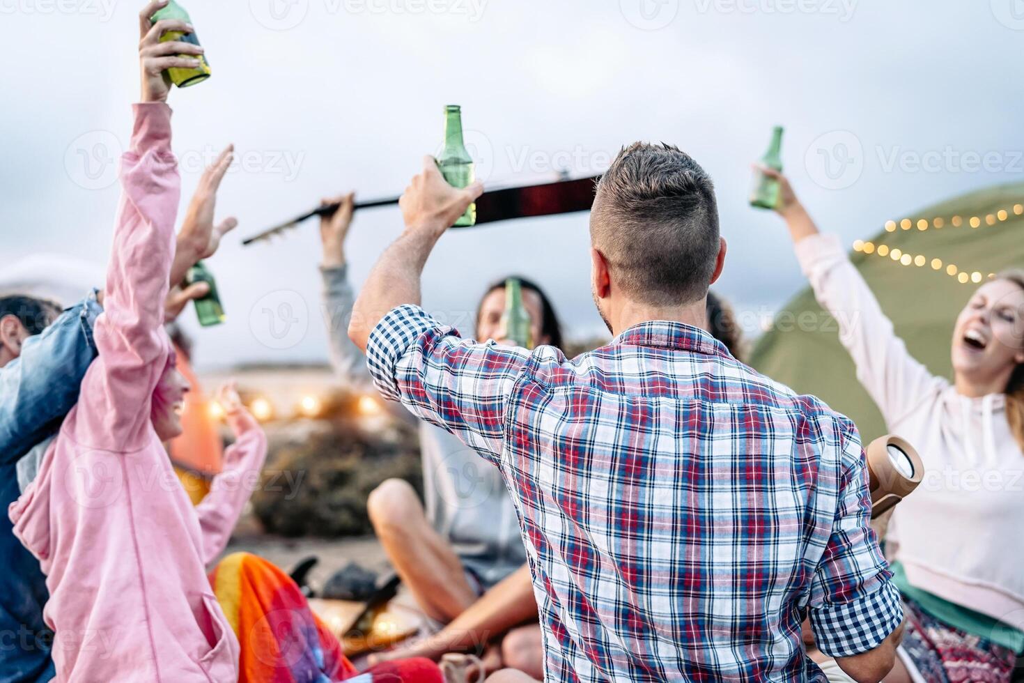 gruppo di amici applauso con birre a barbecue cena su il spiaggia - contento giovane persone campeggio con tenda e avendo divertimento a picnic cena - amicizia, festa e gioventù stile di vita vacanza concetto foto