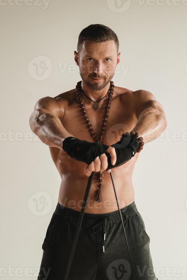 un' uomo con un' nudo torso è impegnato nel forza fitness utilizzando un' gomma da cancellare ciclo continuo in casa foto