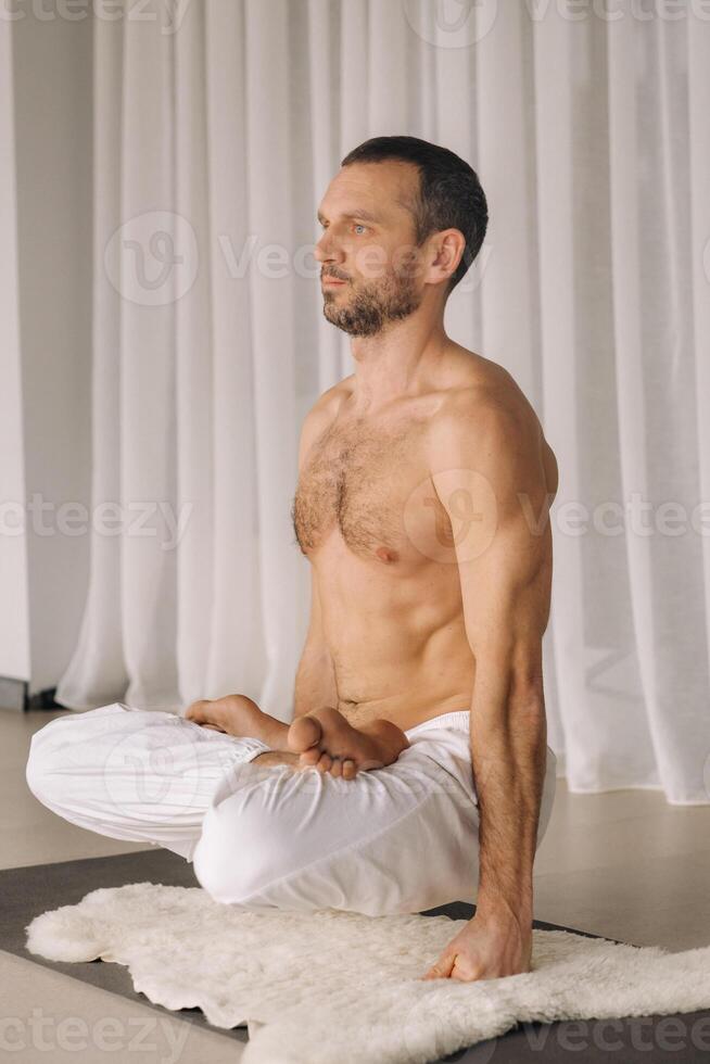 un' uomo con un' spoglio torso fa yoga nel un' fitness camera. il concetto di un' salutare stile di vita foto