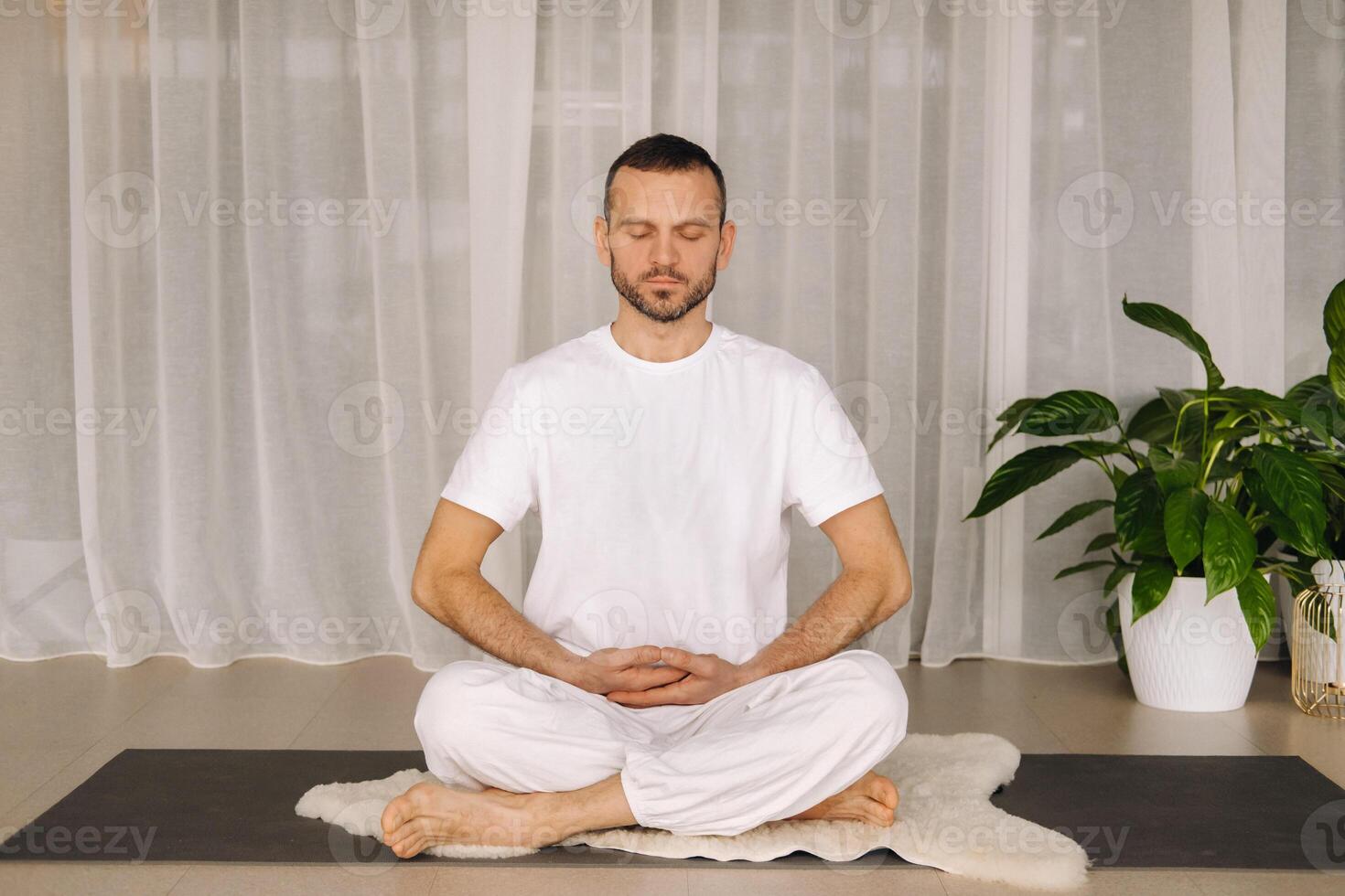un' uomo nel bianca abbigliamento sportivo è fare yoga con un' fitness camera. il concetto di un' salutare stile di vita foto