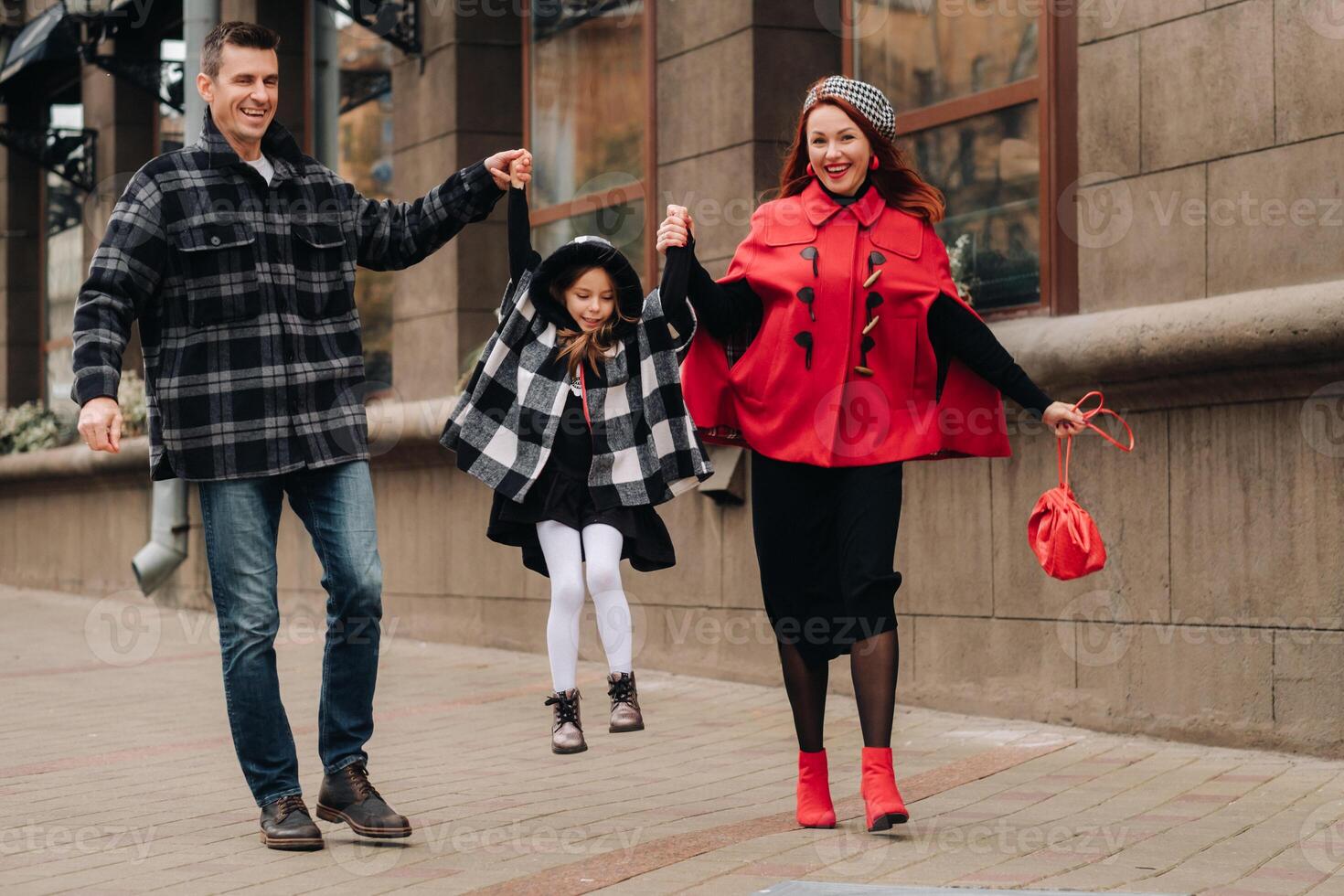 un' elegante famiglia di tre passeggiate nel il città nel autunno Tenere mani foto