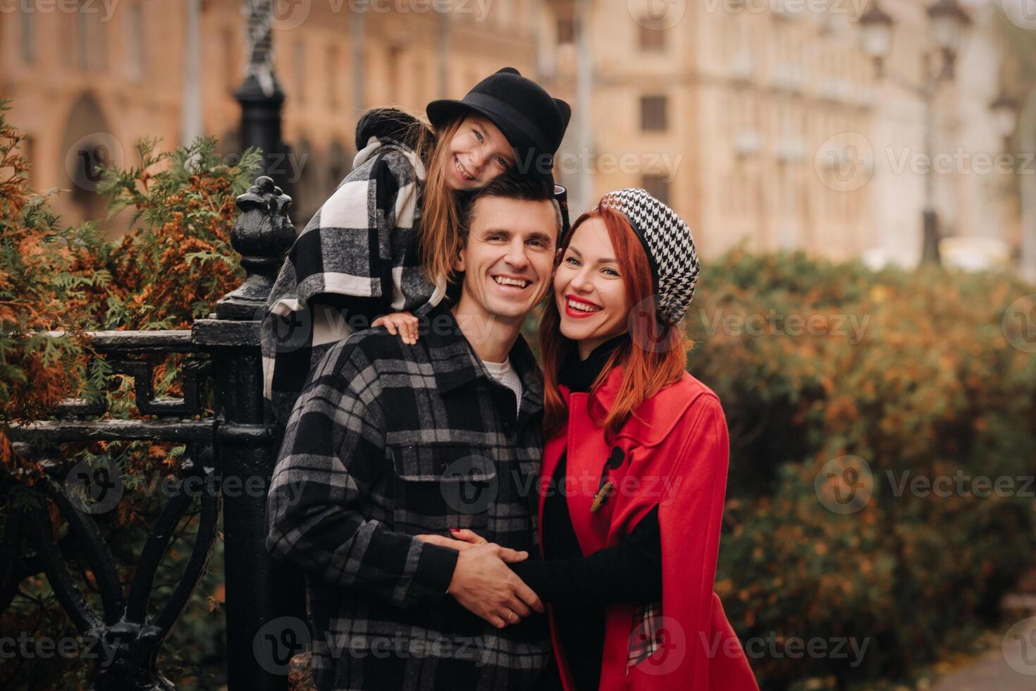 un' elegante famiglia di tre passeggiate attraverso il autunno città in posa per un' fotografo . papà, mamma e figlia nel il autunno città foto