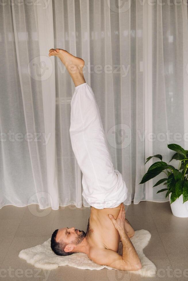 un' uomo con un' spoglio torso fa yoga nel un' fitness camera. il concetto di un' salutare stile di vita foto