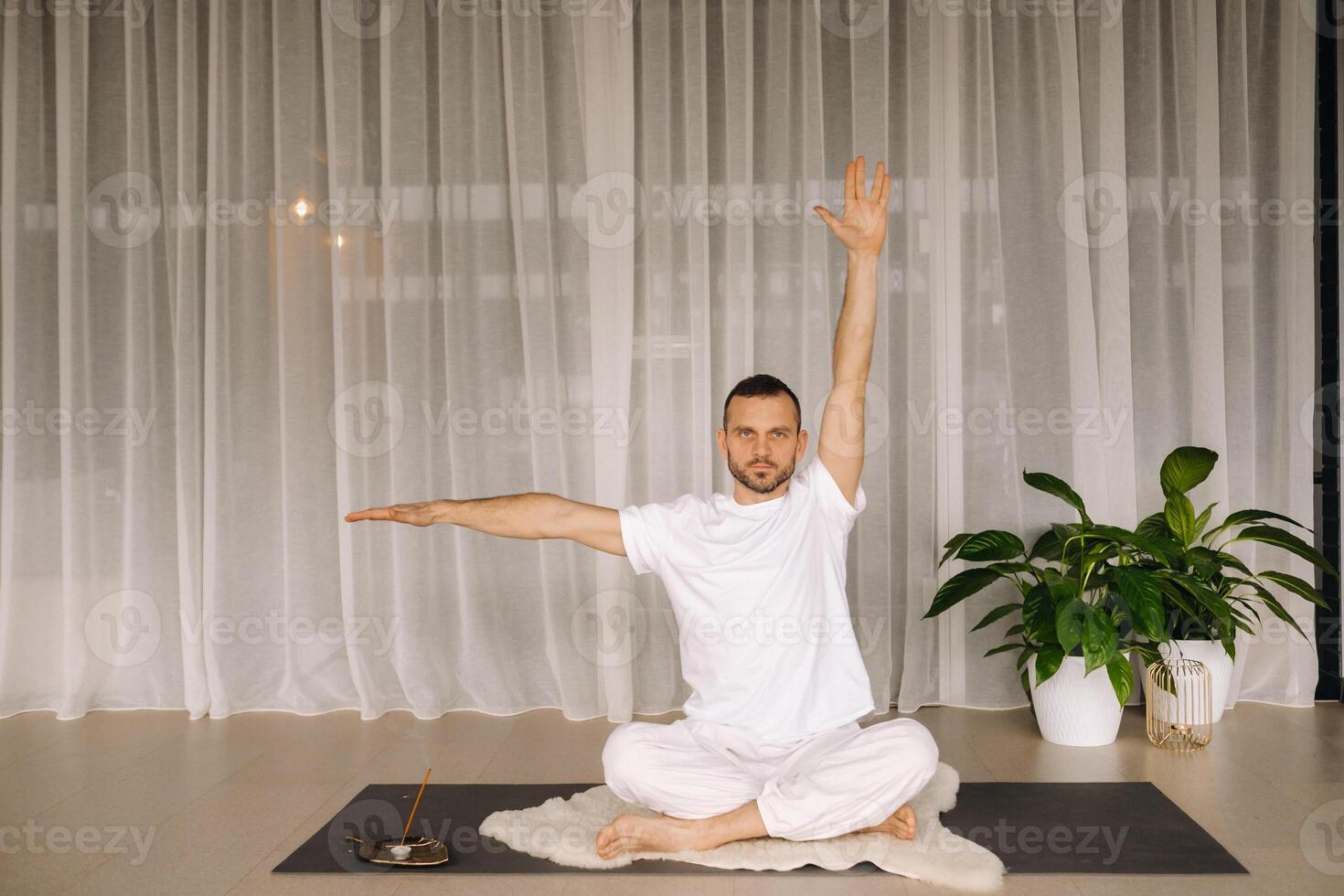 un' uomo nel bianca abbigliamento sportivo è fare yoga con un' fitness camera. il concetto di un' salutare stile di vita foto