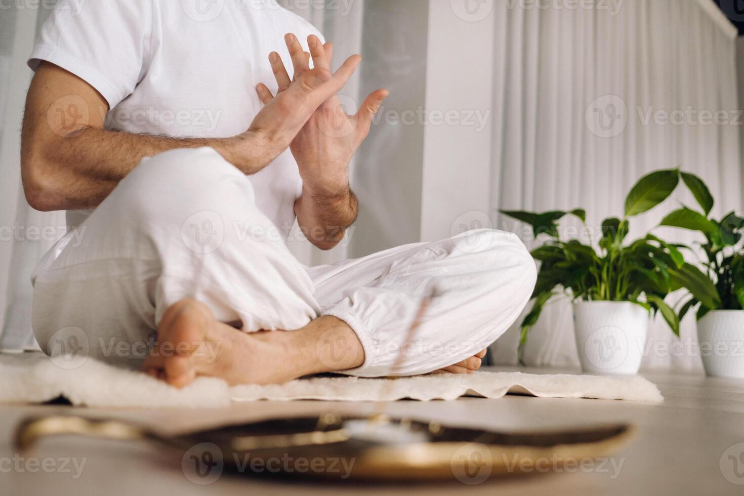 avvicinamento di un' uomo nel bianca abbigliamento sportivo fare yoga nel un' fitness camera con un' balgovon. il concetto di un' salutare stile di vita foto
