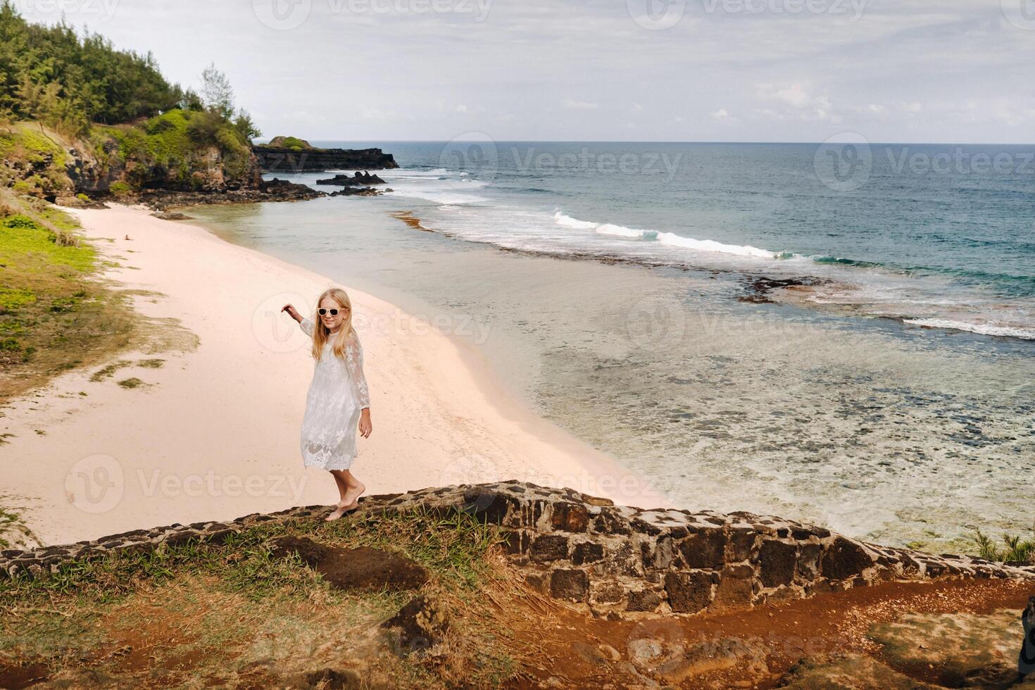 un' ragazza nel un' bianca vestito su il grigio-grigio spiaggia su il isola di mauritius foto