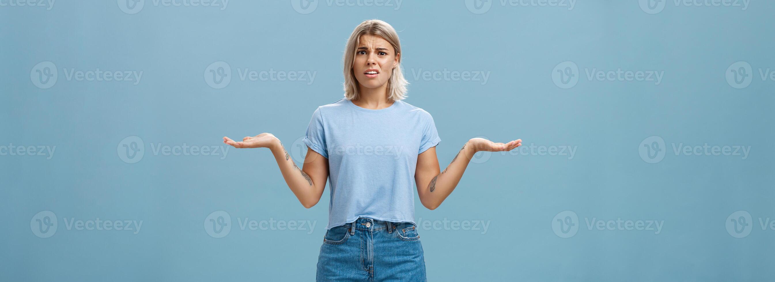 ragazza sensazione lotte per capire che cosa succedendo. confuso perplesso intenso bella vista femmina con giusto capelli alzando le spalle con mani diffusione a parte nel scontento all'oscuro posa in posa al di sopra di blu parete foto