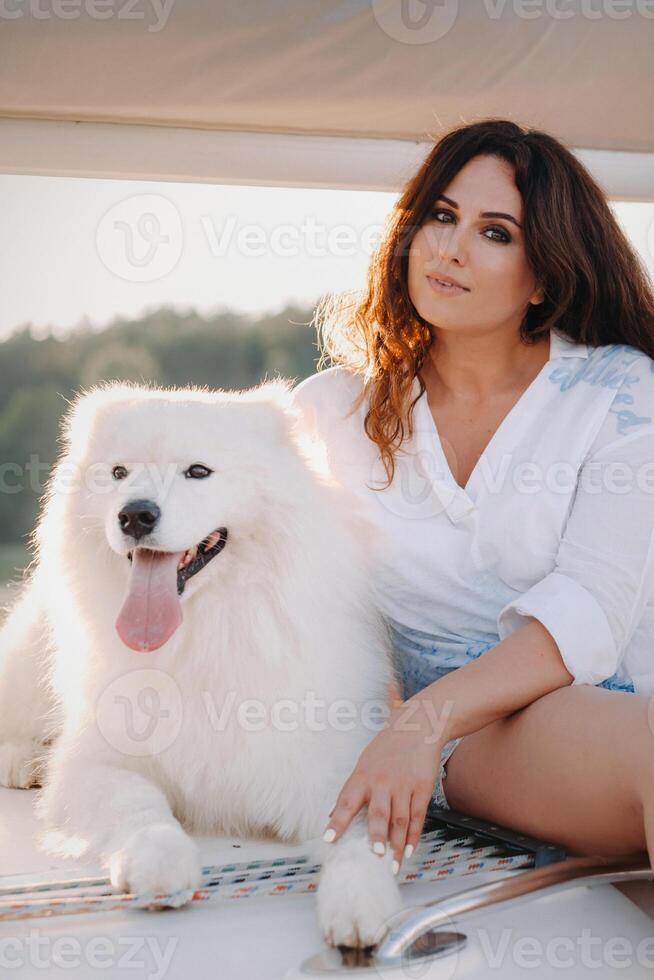 un' contento donna con un' grande bianca cane su un' bianca yacht nel il mare foto