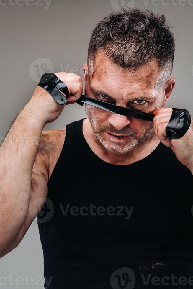 su un' grigio sfondo sta un' malconcio uomo nel un' nero t camicia guardare piace un' combattente e preparazione per un' combattimento foto