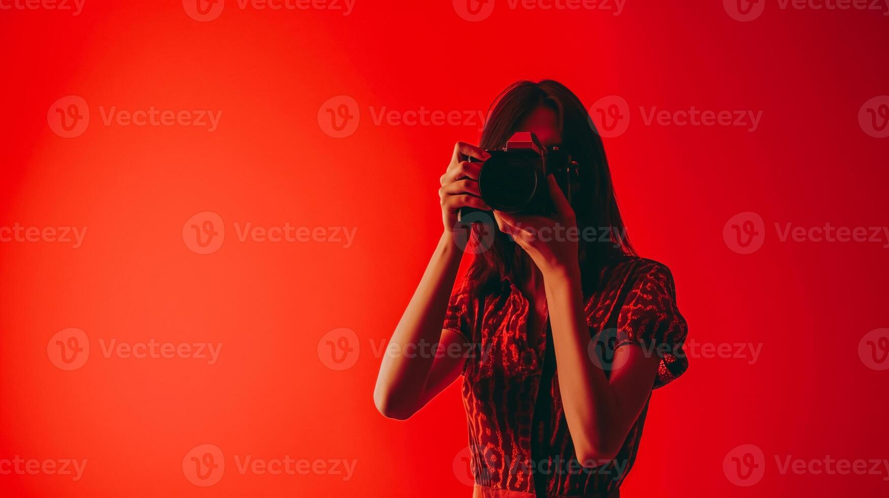 ai generato staglia asiatico femmina fotografo Tenere telecamera contro un' vivace rosso sfondo con ampio copia spazio, ideale per creativo concetti e design sfondi foto