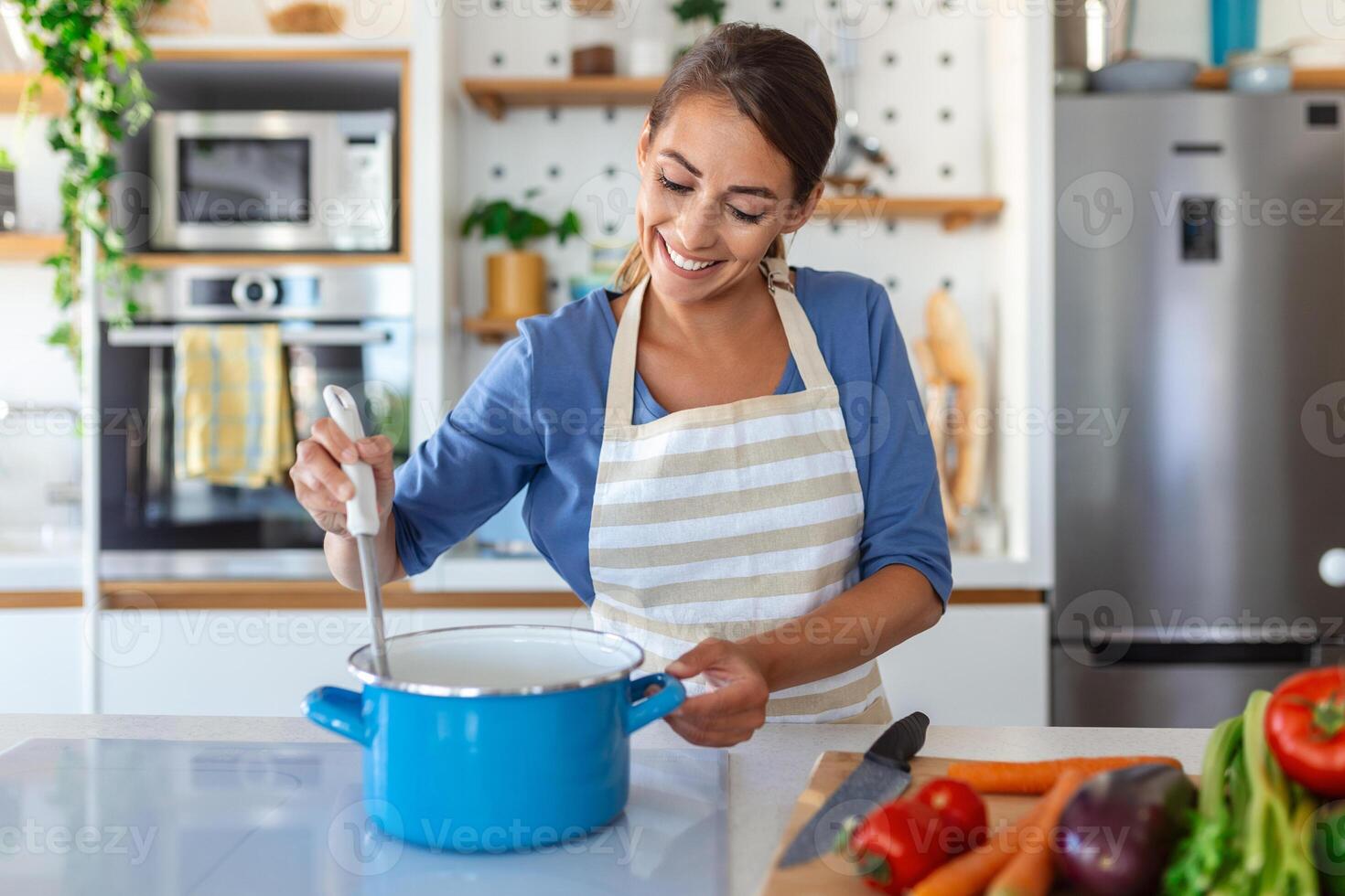 contento giovane donna cucinando degustazione cena nel un' pentola in piedi nel moderno cucina a casa. casalinga preparazione salutare cibo sorridente . domestico e nutrizione. dieta ricette concetto foto