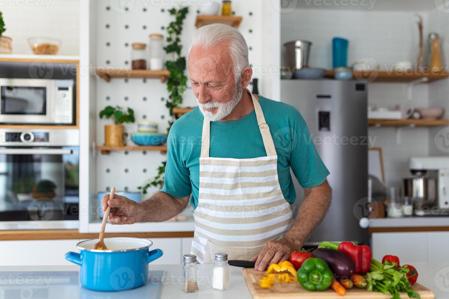 contento anziano uomo avendo divertimento cucinando a casa - anziano persona preparazione Salute pranzo nel moderno cucina - pensionato stile di vita tempo e cibo nutrizione concetto foto