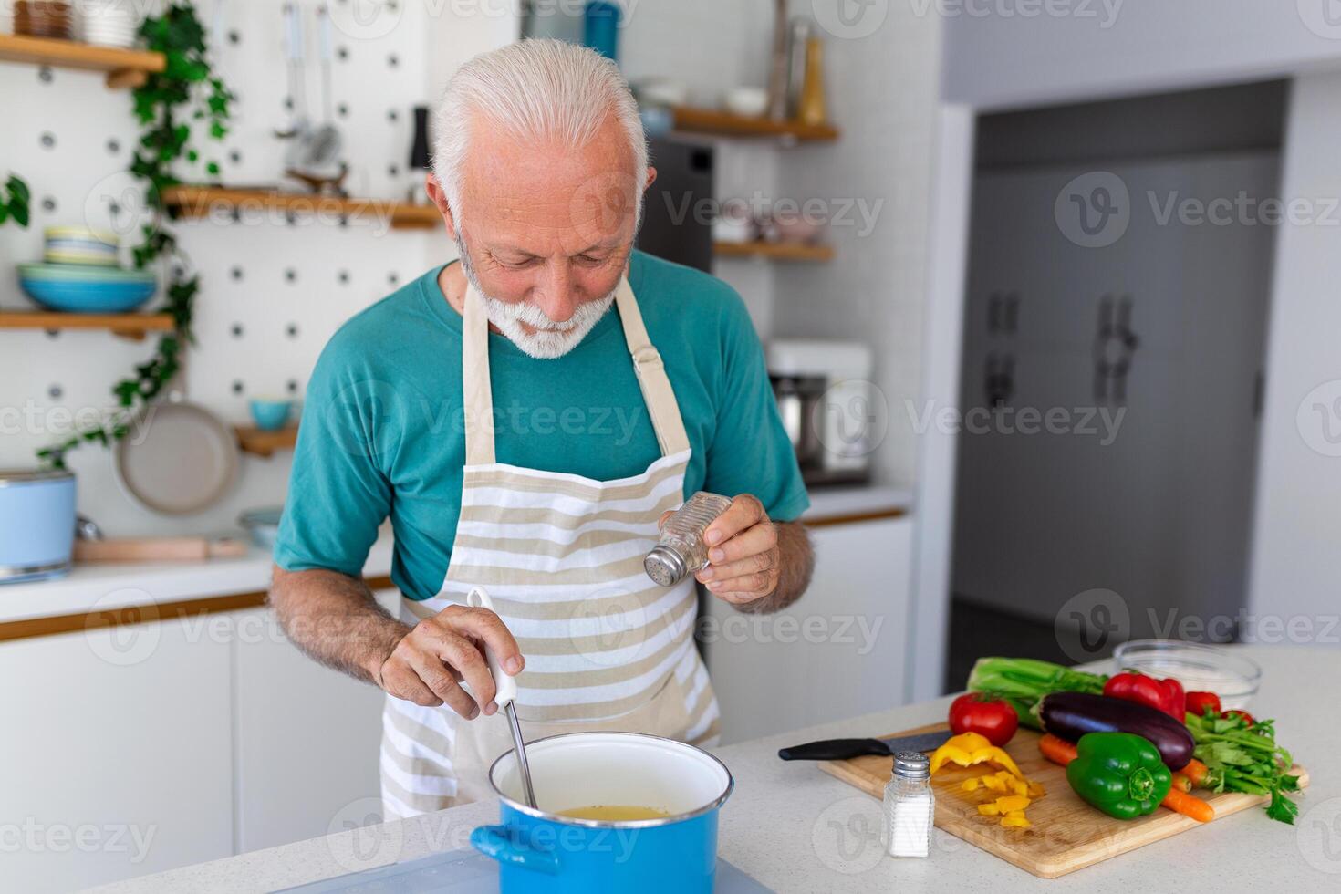 contento anziano uomo avendo divertimento cucinando a casa - anziano persona preparazione Salute pranzo nel moderno cucina - pensionato stile di vita tempo e cibo nutrizione concetto foto