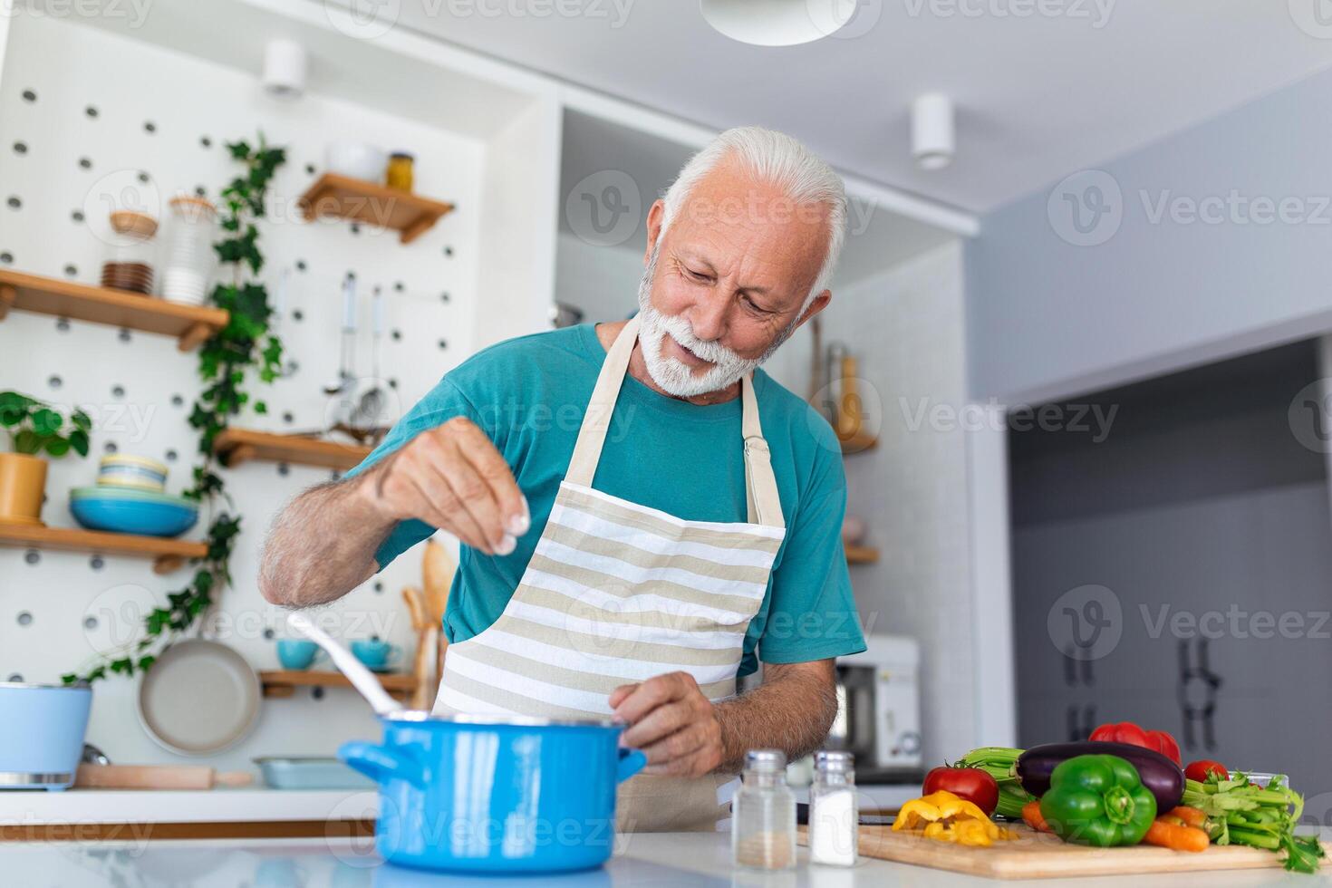 contento anziano uomo avendo divertimento cucinando a casa - anziano persona preparazione Salute pranzo nel moderno cucina - pensionato stile di vita tempo e cibo nutrizione concetto foto