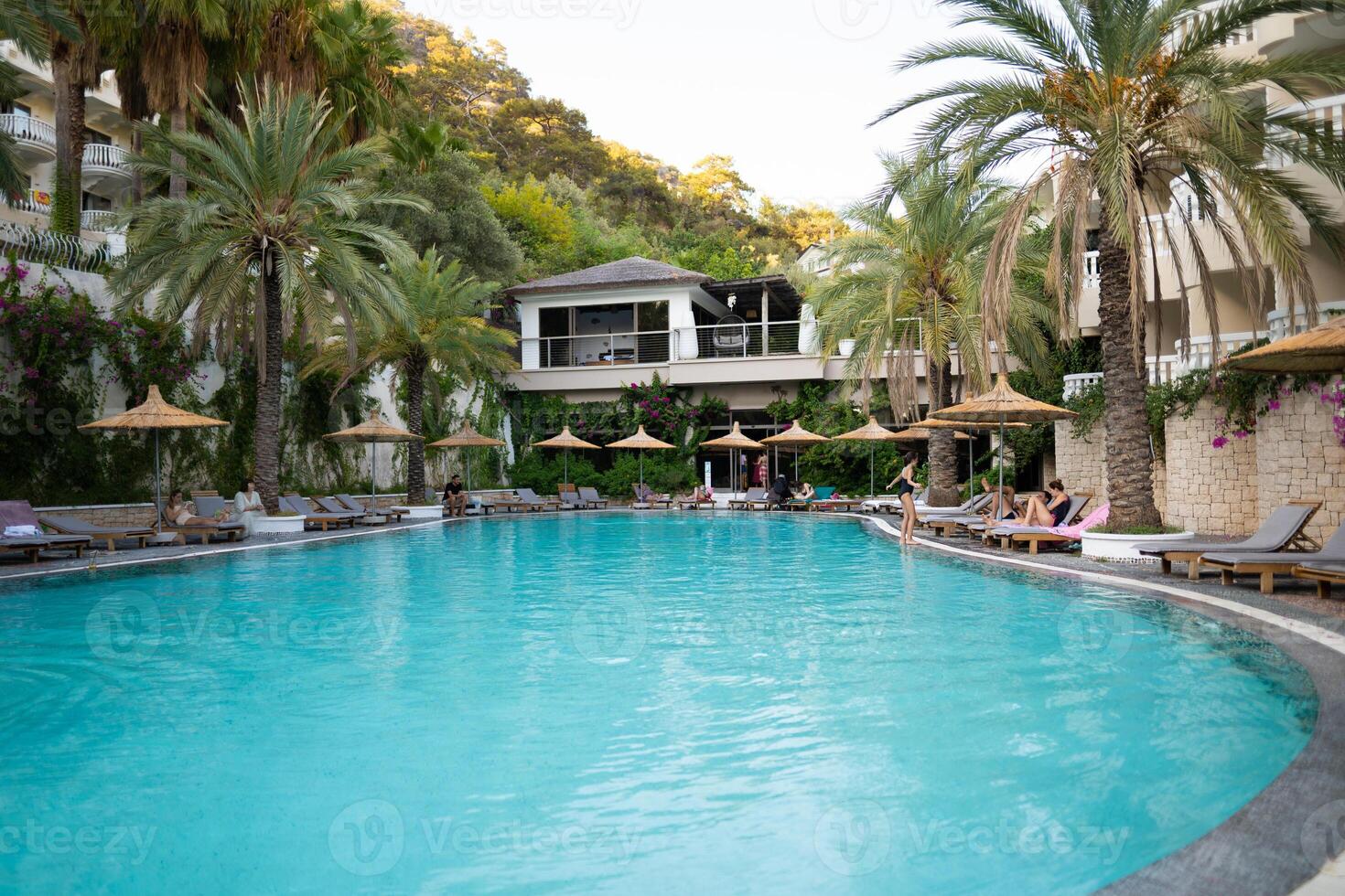 un' grande all'aperto piscina su il Hotel motivo con blu acqua e palma alberi foto