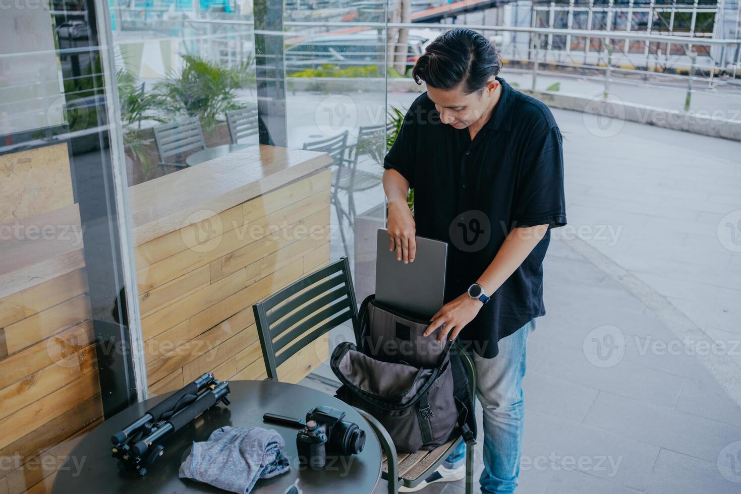 giovane indonesiano uomo preparazione o Imballaggio fotografia attrezzatura e Abiti in un' zaino. vacanza viaggio concetto. foto