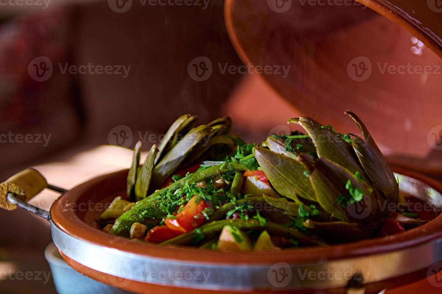 carciofi e verdure condito con tritato coriandolo e prezzemolo erbe aromatiche, servito nel tradizionale marocchino tagine argilla piatto foto