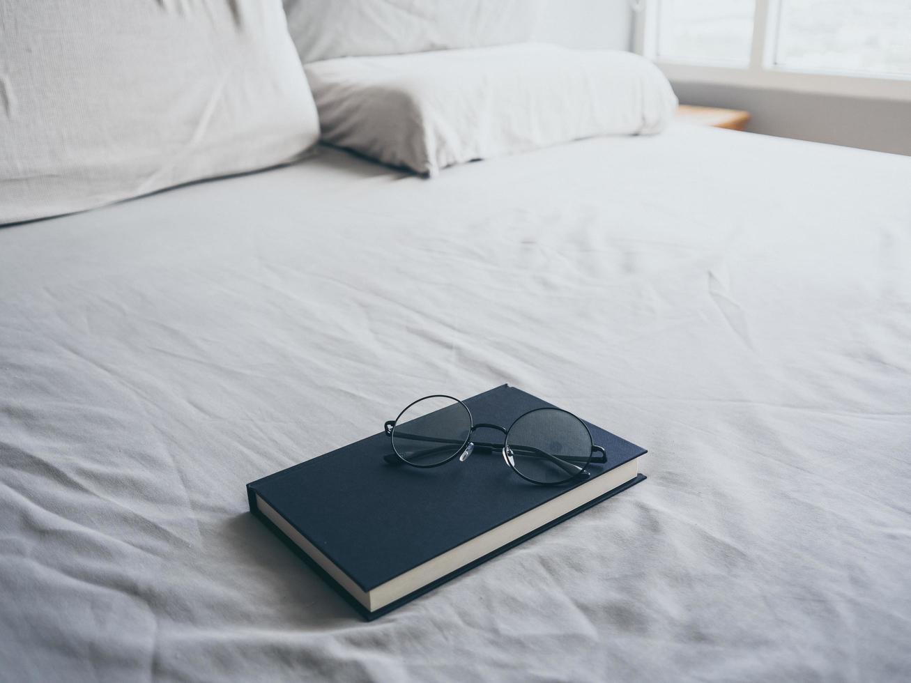 occhiali da vista e libro in camera da letto per leggere e rilassarsi. foto