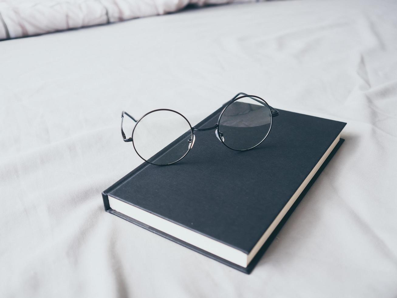 occhiali da vista e libro in camera da letto per leggere e rilassarsi. foto