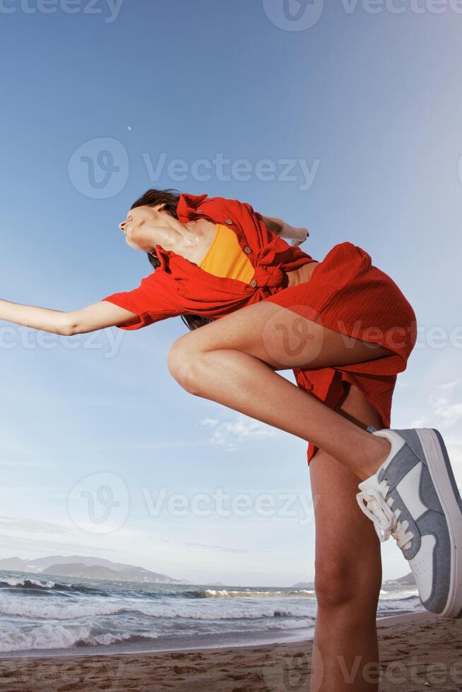 sorridente donna danza con gioia a il soleggiato spiaggia foto