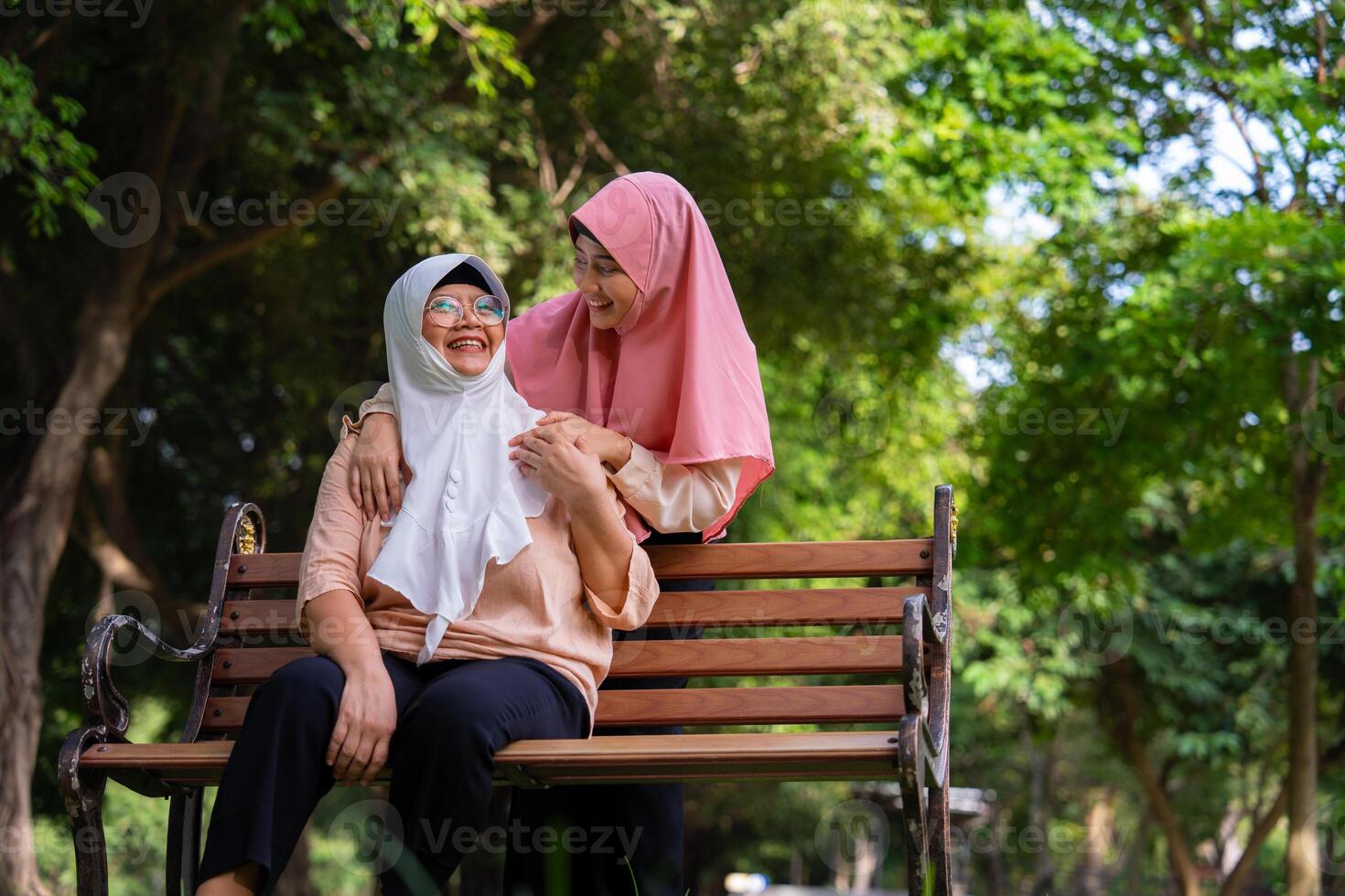 musulmano attento badante o infermiera assunzione cura di il paziente nel il ospedale parco. contento musulmano madre nel hijab abbracciare figlia. concetto di risparmi e anziano Salute assicurazione, un' contento famiglia foto