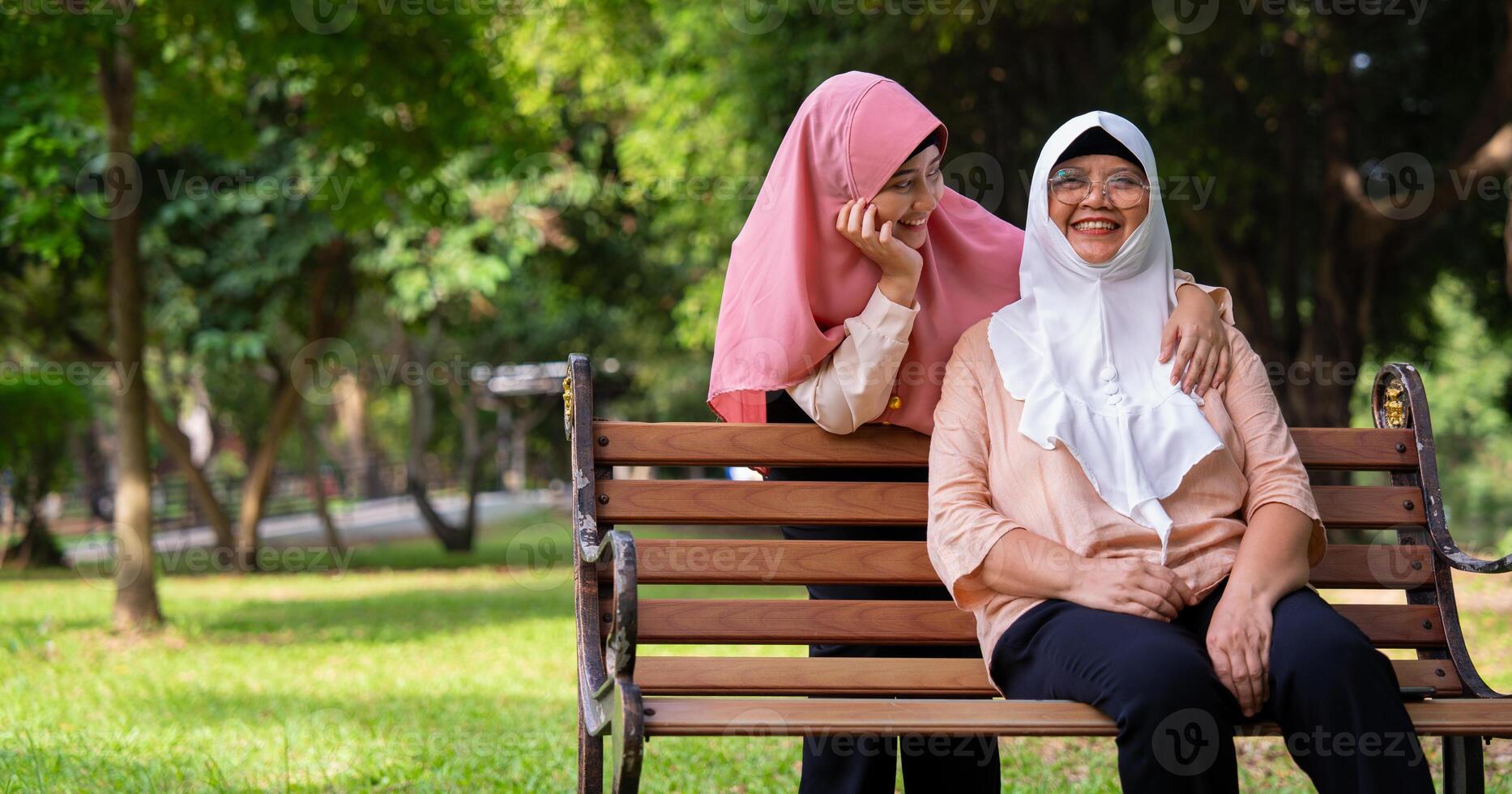 musulmano attento badante o infermiera assunzione cura di il paziente nel il ospedale parco. contento musulmano madre nel hijab abbracciare figlia. concetto di risparmi e anziano Salute assicurazione, un' contento famiglia foto