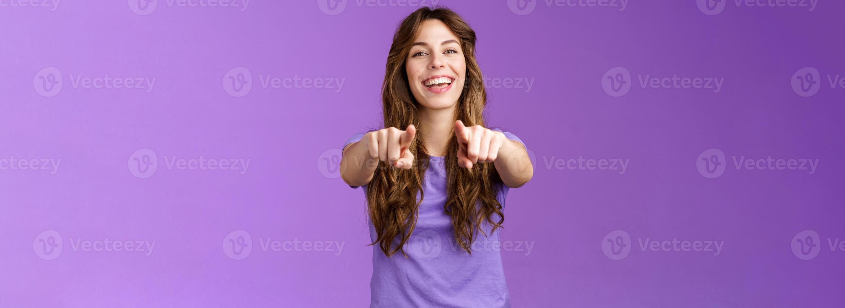 suo voi. amichevole lieto gioioso contento dai capelli ricci ragazza puntamento dita telecamera sorridente a grandi linee ridendo congratularsi amico cantando canzone indicando fidanzato rendere scelta In piedi viola sfondo foto