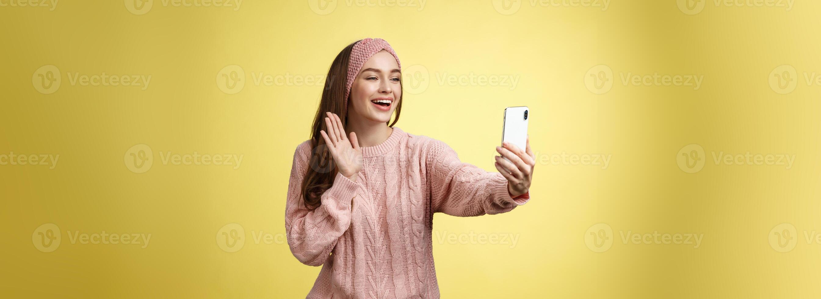 affascinante estroverso fidanzata avendo in linea video Chiacchierare, Tenere smartphone agitando a Telefono telecamera detto Ciao parlando attraverso video chiamata sorridente amichevole durante piacevole conversazione, registrazione saluto foto