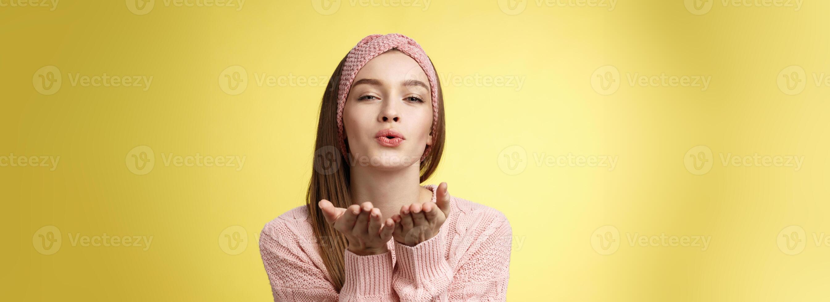 contento san valentino giorno. affascinante romantico e sensuale giovane provocante donna nel a maglia fascia per capelli, maglione estendendosi palme vicino piegato labbra invio aria mah, soffiaggio bacio tenero e dolce foto