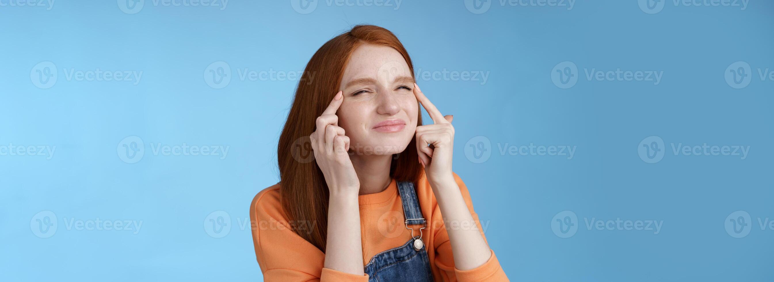 carino divertente europeo testa Rossa ragazza dimenticato bicchieri provando leggere sospiro allungare palpebre strabismo accigliato focalizzata Guarda superiore sinistra angolo perplesso vedere che cosa accadendo, in piedi blu sfondo foto