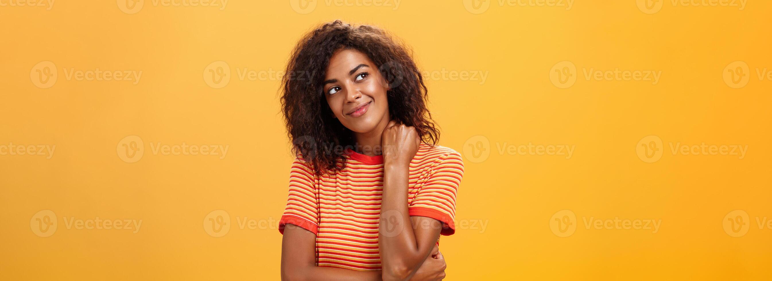 carino e dolce sognante di carnagione scura ragazza con crudele acconciatura ribaltamento testa sorridente a partire dal diletto e felicità toccante collo tenero guardando a superiore sinistra angolo pensiero o essere nostalgico foto